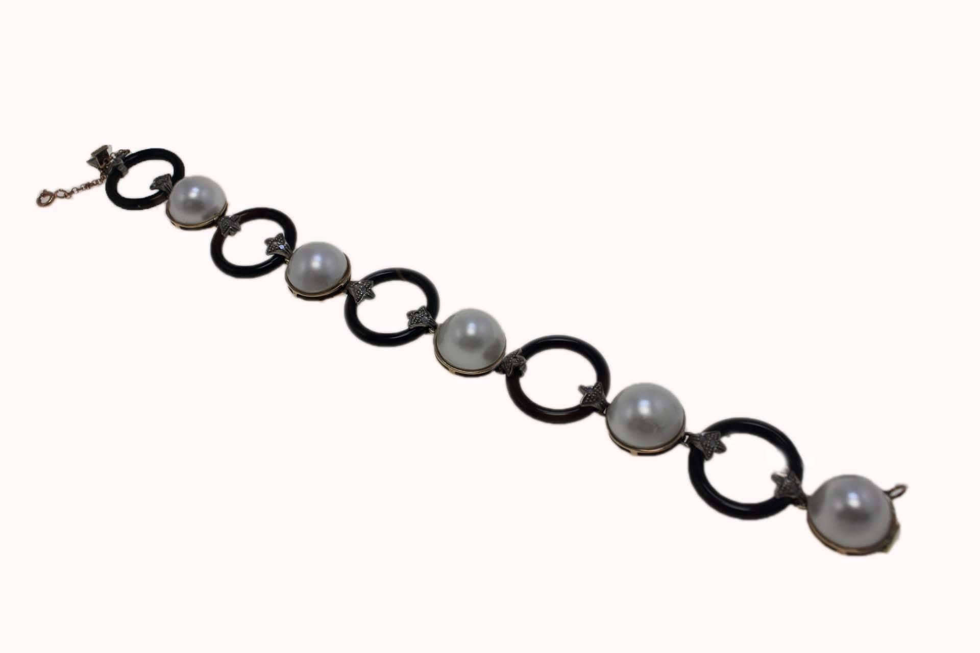 Classic and elegant link bracelet compose of circle of onyx  alternating with pearls and linked trough diamonds leaves. All is mounted in 9 Kt rose gold and silver.
Tot weight 22.3 g
Diamonds 0.17 ct
Pearls 5.43 g diameter 13/14 mm
Onyx 5.50 g

Rf.
