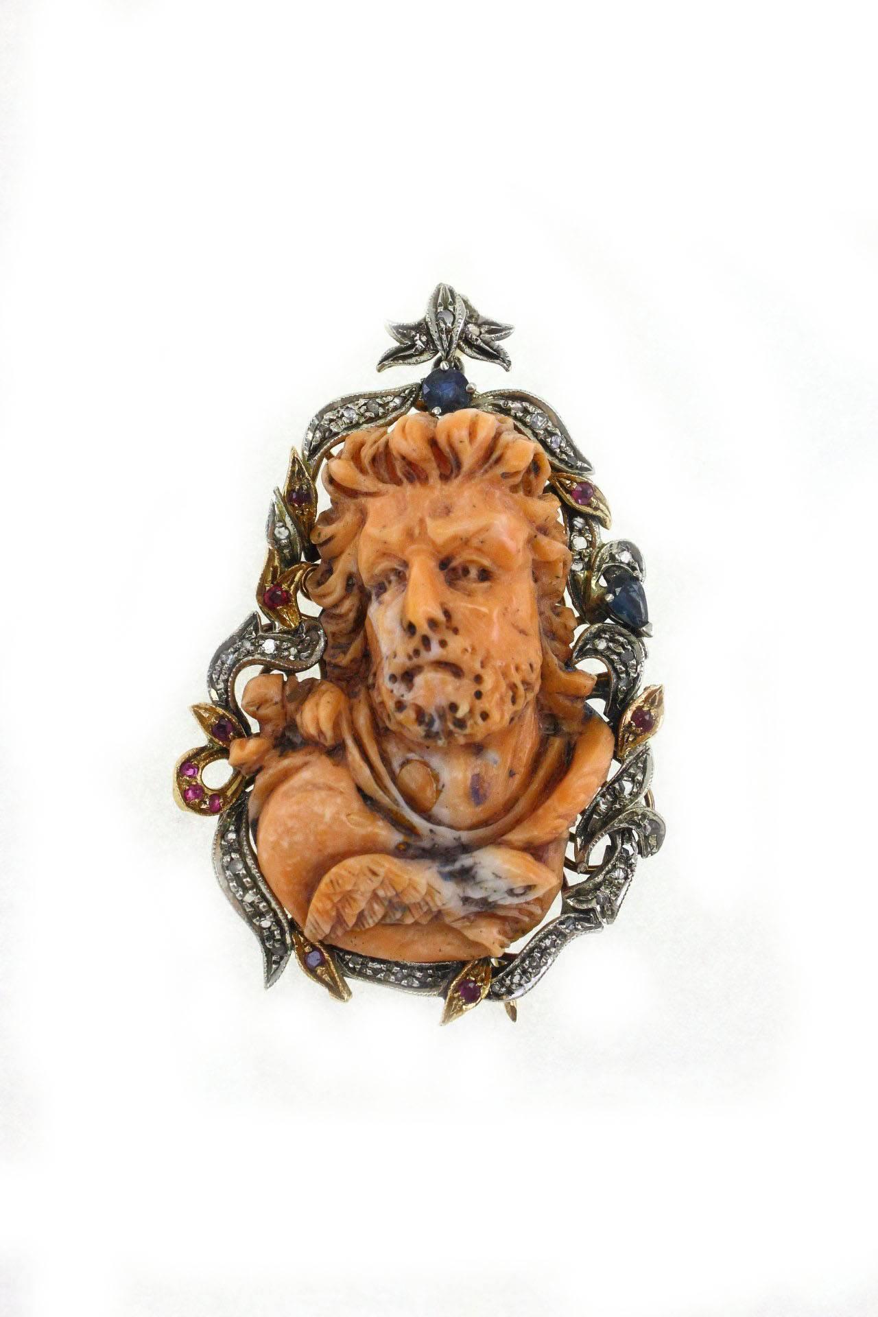 Victorian pendant/brooch in 9kgold and silver with a central coral carved face surrounded by  diamonds, blue sapphires and rubies.

diamonds 0.43 Kt
blue sapphire and rubies  0.95 kt
coral 13.60gr 
tot weight 28.5gr
US size width 1.57 inches Length