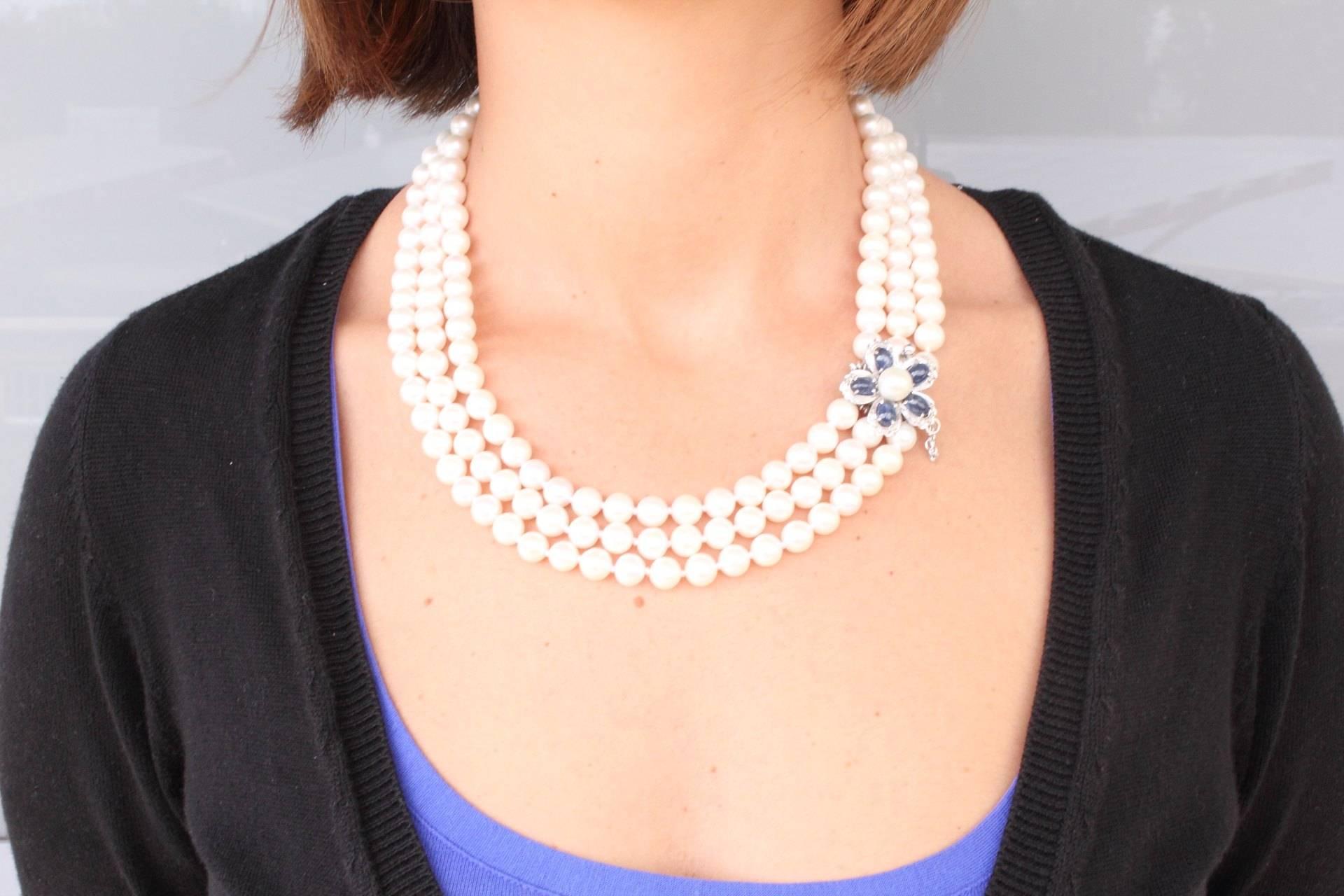 Exquisite necklace composed with a 3 strands of unbleished pearls. The fascinating detail of the susta with a pleasing blue sapphire and diamonds that are set in the 5 petals and a pearl hart. 
US Size
Width Susta: 0.99 inches
Lenght 1st strand :