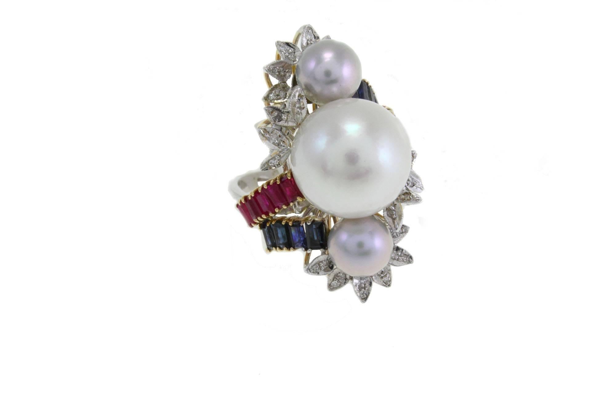 Special ring in 14kt white and yellow gold composed of 3 pearls surrounded by rubies and blue sapphires, with leaves of diamonds.

diamonds 0.15kt
rubies and sapphires 2.88 kt
pearls 5.40gr
tot weight 13.5gr
US Size
Width 0.90 in
Length 1.30