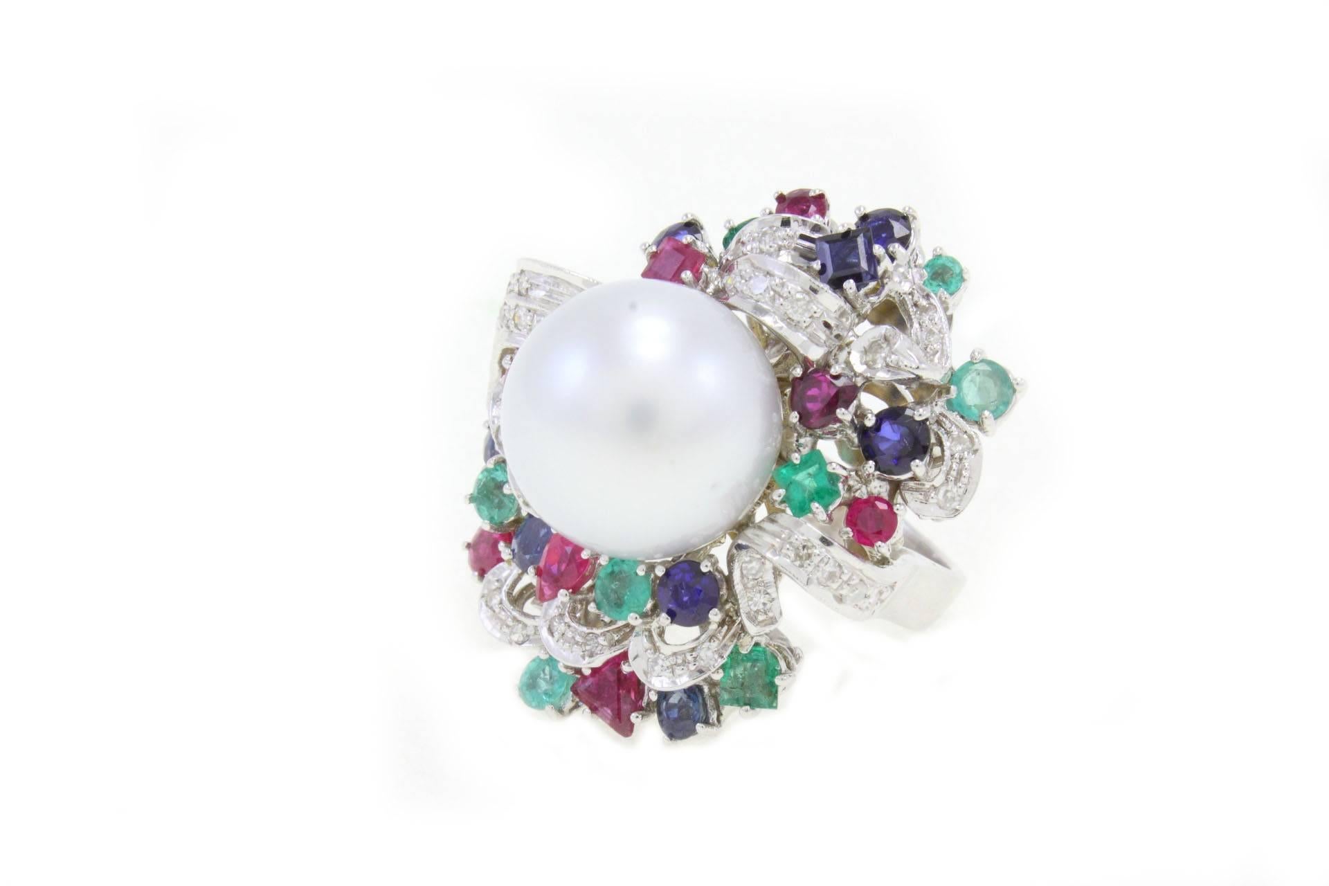 Shiny ring in 14 Kt white gold composed of a central Australian  pearl surrounded by diamonds, emeralds, blue sapphires and rubies.

Diamonds 0.71 kt
gems 4.97 Kt  
Pearl 4.25gr
US Size                                 
Width 1.10 inch               