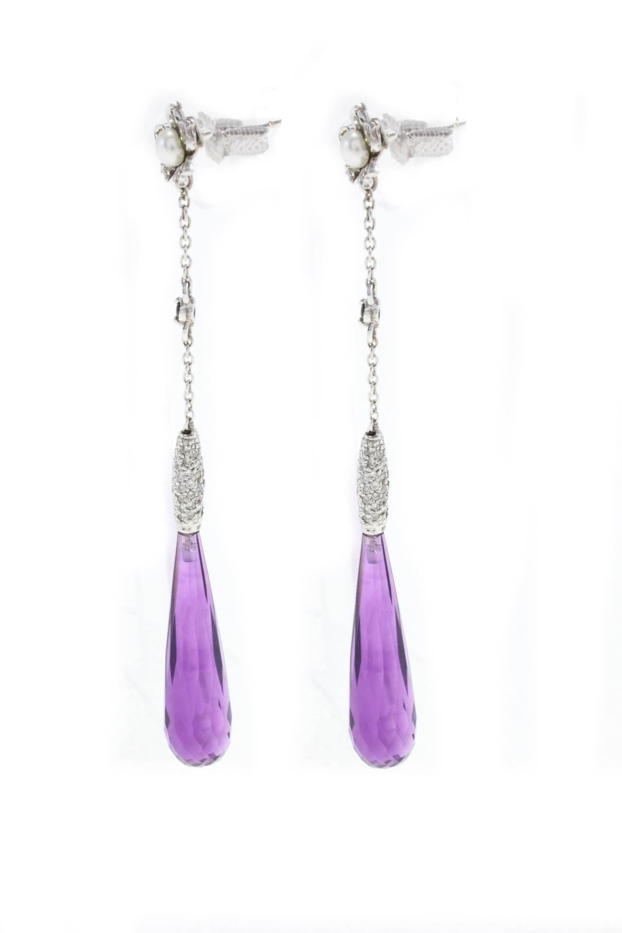 Classic and shapely earrings mounted on  18K white gold(2.49gr) embellished with a teardrop of amethyst(4.70 gr) and diamonds (1.05 Kt),on the top of the teardrop there is a little daisy with a pearl in the middle (0.40gr).
These earrings look