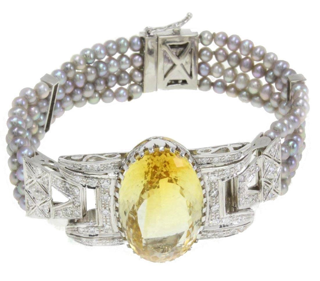 Sparkling bracelet in 14Kt of white gold composed of a central shiny topaz, diamonds that links it to 3 rows of grey pearl.
topaz (24.40Kt)
grey pearls (8.70gr) 
diamonds (2.11Kt),
US Size
Width 0.98 inch
Length 6.89 inch
tot weight 36.4gr
Rf.