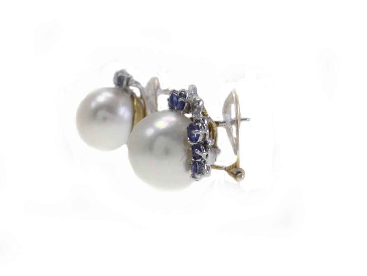 Elegant earrings in 14Kt gold and white gold composed of a medium size pearl surrouded by a little crown of diamonds and blue sapphires. These gemstone together make up a delightful pairs of earrings that you will not resist to