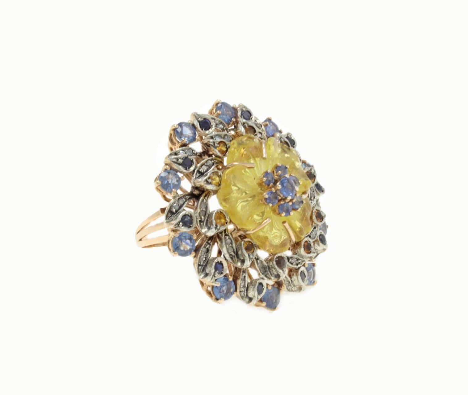 Encantador anillo de oro de 9 quilates y plata compuesto por un brillante cuarzo amarillo con un centro de zafiros azules rodeado de zafiros azules, topacios y diamantes.
zafiros azules (3,89Kt) 
topacios (0,61Kt) 
diamantes (0,30Kt) 
cuarzo