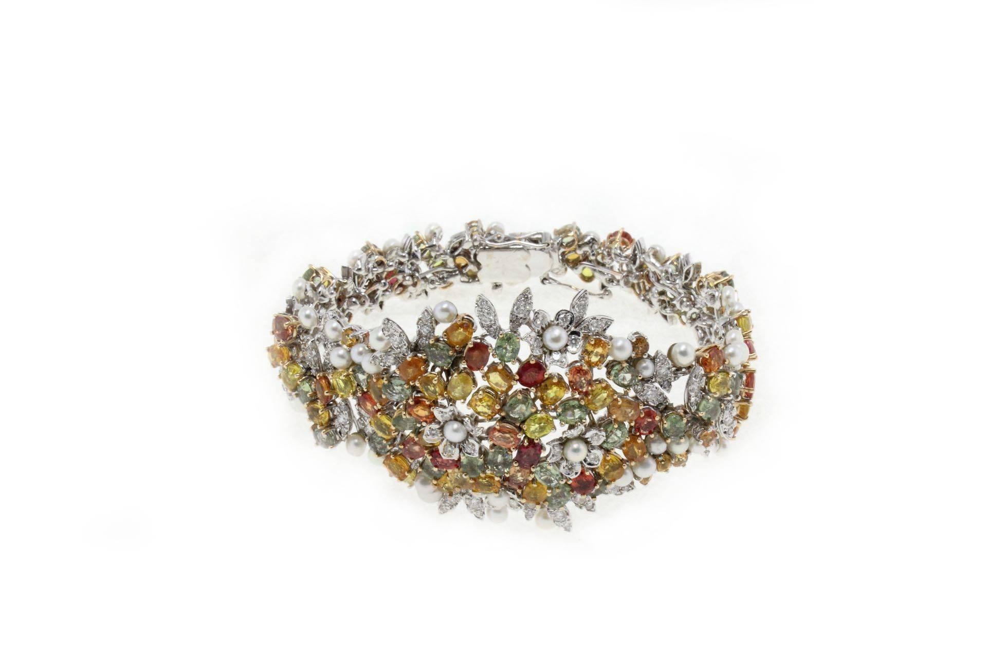 Mounted with 14Kt white gold and details of gold, there is a bouquet of  diamonds (2.68Kt) who are naturally matched with the drops of multicolors sapphires, (31.50Kt) and little pearls(1.40gr) to embellished them all. This retro bracelet is the