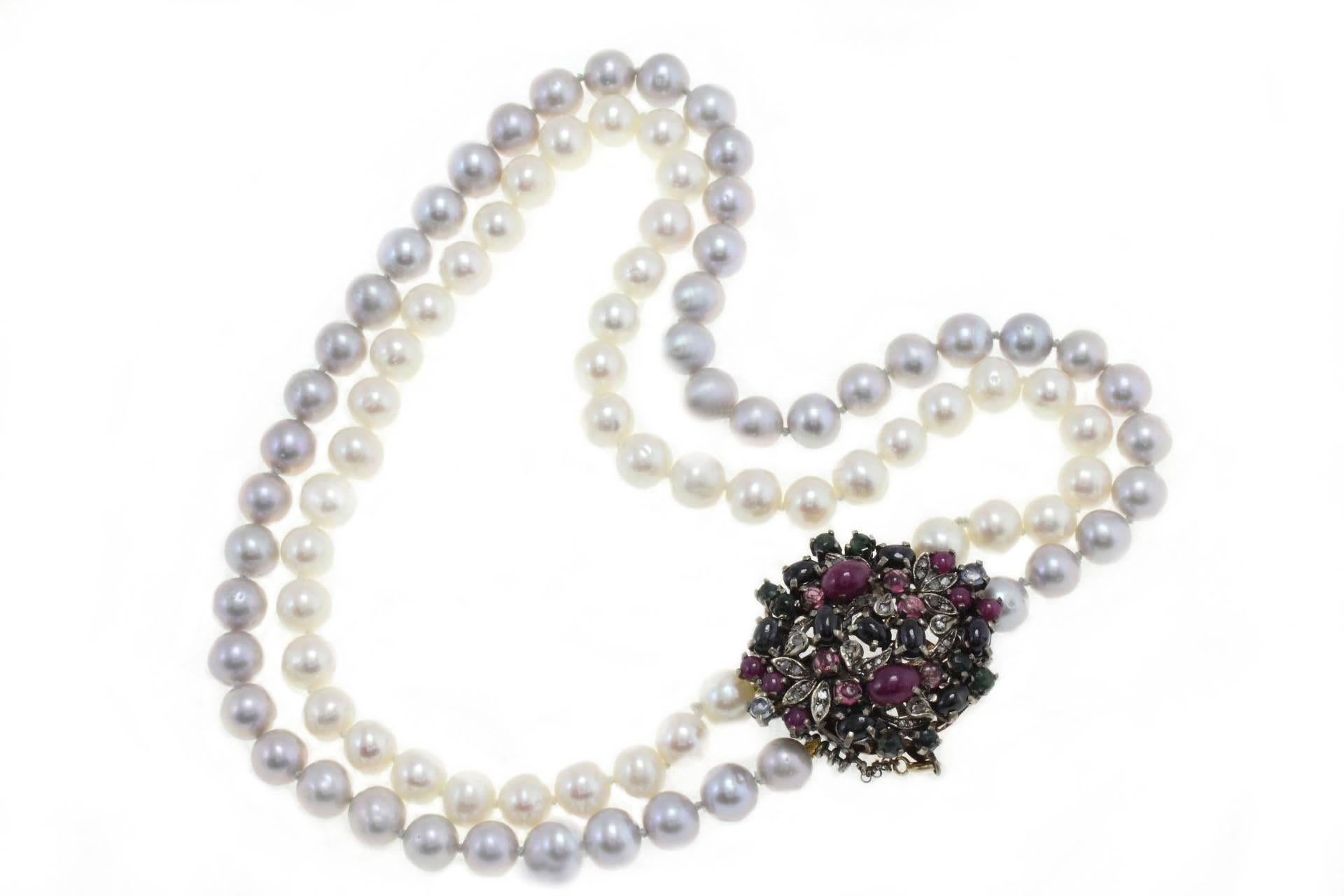 Beaded necklace composed of two rows of pearls (one gray, one white) with a clasp  in 9kt gold and silver mounted with diamonds,  rubies, blue sapphires and emeralds.

pearls (86.10 gr) (9 mm), 
diamonds (0.27 kt) 
rubies, blue sapphires and