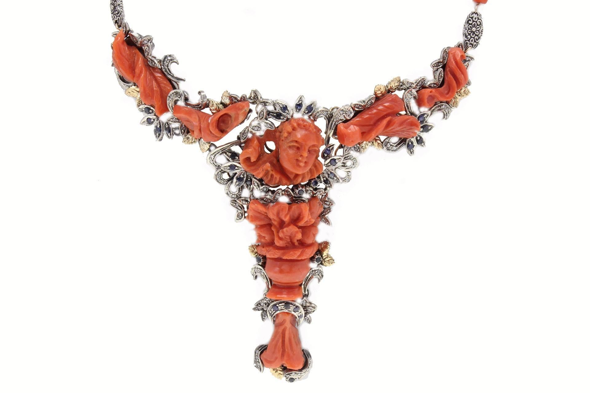 Completely handmade necklace in 9 kt gold and silver with carved coral, diamonds and blue sapphires.

coral (23.20 gr), 
diamonds (0.87 kt) 
blue sapphires (2.02 kt)
tot.weight 70.80
r.f  ocfu