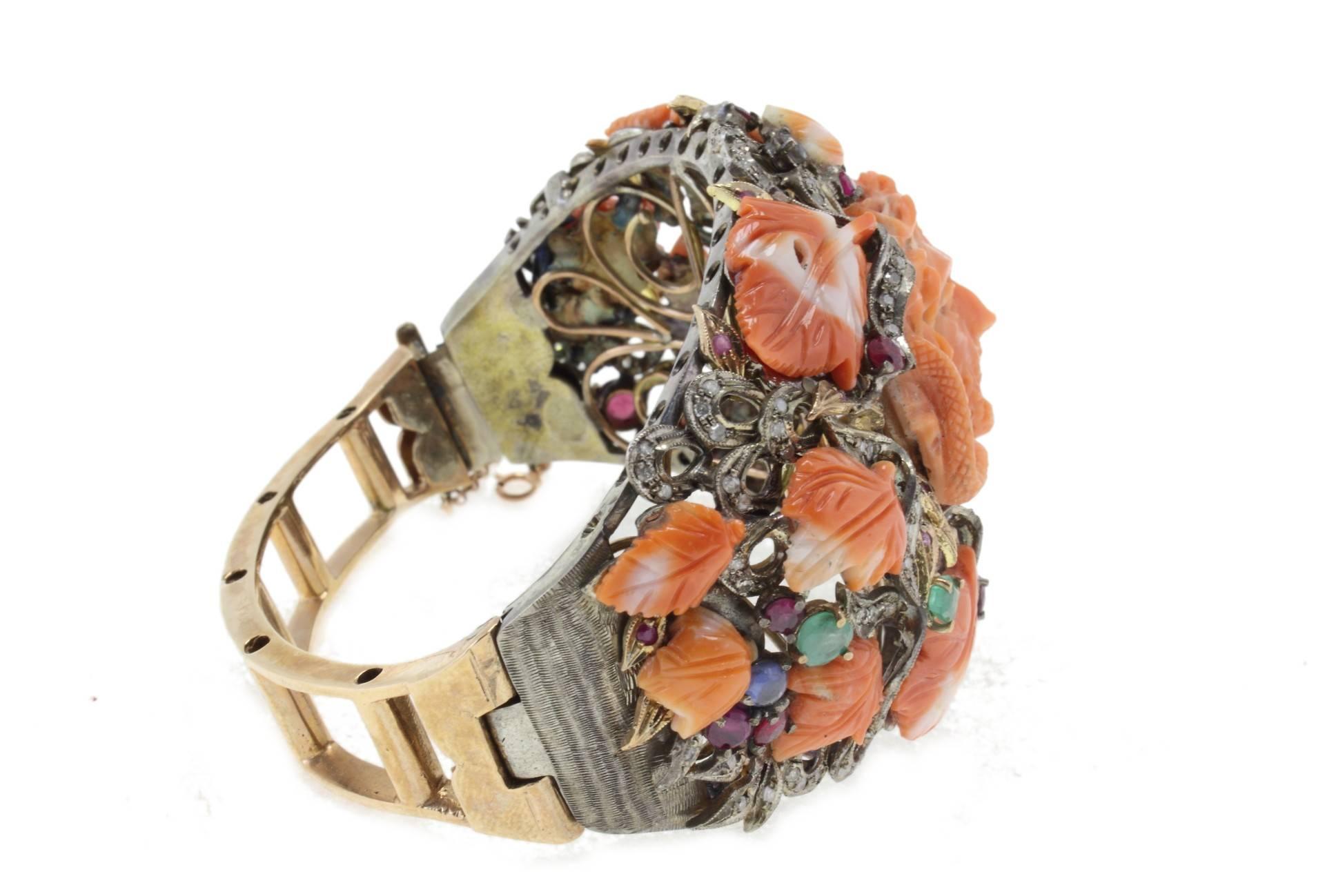 9kt gold and silver bracelet composed of diamonds, blue and yellow sapphires, emeralds and carved coral (face and leaves shaped). 

Diamonds 1.66 kt
Sapphires, Emeralds, Rubies 3.87 kt
Coral 17.00 gr
Tot.Weight 76.60 gr
R.F ogeh