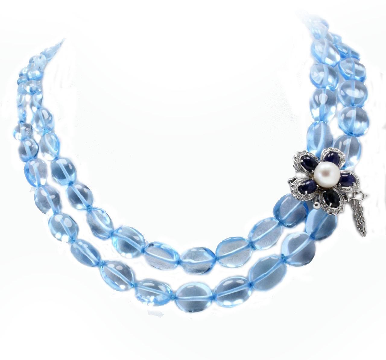 Multi-Strands necklace in 14kt white gold composed of 2 topaz rows, and flower shaped clasp mounted with diamonds blue sapphires and one pearl in the center.
Diamonds 0.38 kt
Blue Sapphires 5.67 kt 
Pearl 0.90 gr
Topaz 110.70 gr
Tot.Weight 121.30