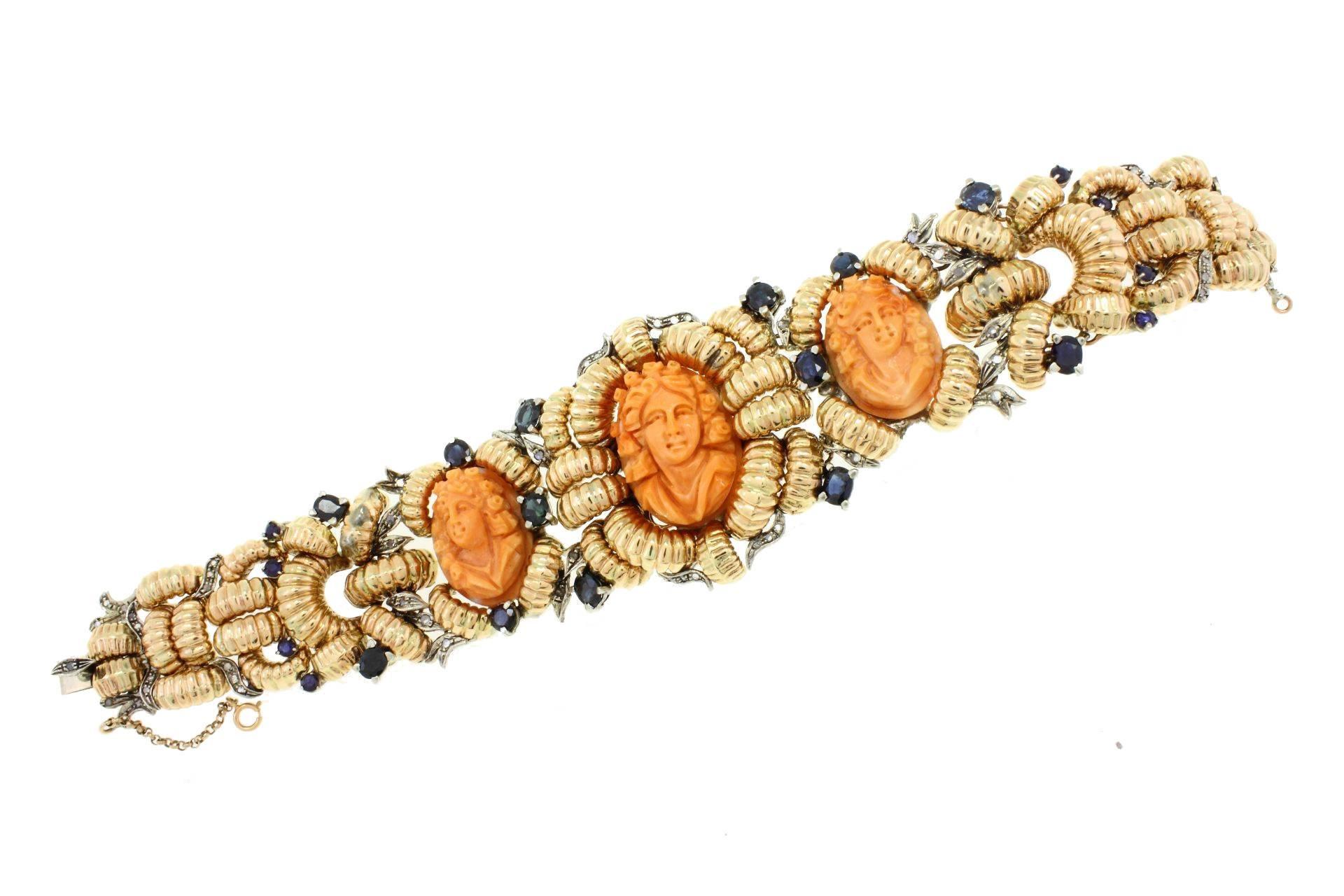 High quality design bracelet in 9Kt gold and silver adorned with diamonds and blue sapphires, which surround the three coral cameos.
diamonds(0.47Kt) 
blue sapphires(7.08Kt)
coral(10.00gr) 
Tot weight 75.6 gr
r.f. 780339

For any enquires, please