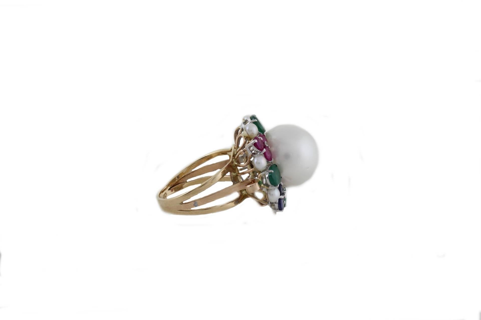 Classic ring in 14 Kt yellow gold and details in 14Kt white gold with a crown of precious stones ( emerald, rubies and blue sapphires for a tot carats of 3.33) with shiny point of diamonds(0.10Kt) and a central pearl with a diameter of 13mm and the