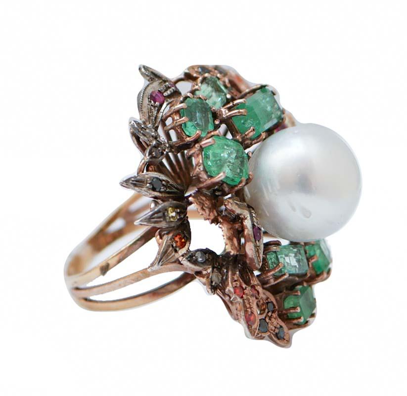 Anello Retrò in oro rosa 9 kt e struttura in argento con perla centrale circondata da smeraldi e foglie tempestate di diamanti, rubini, zaffiri e pietre multicolore.
Questo anello è stato realizzato totalmente a mano da maestri orafi italiani ed è