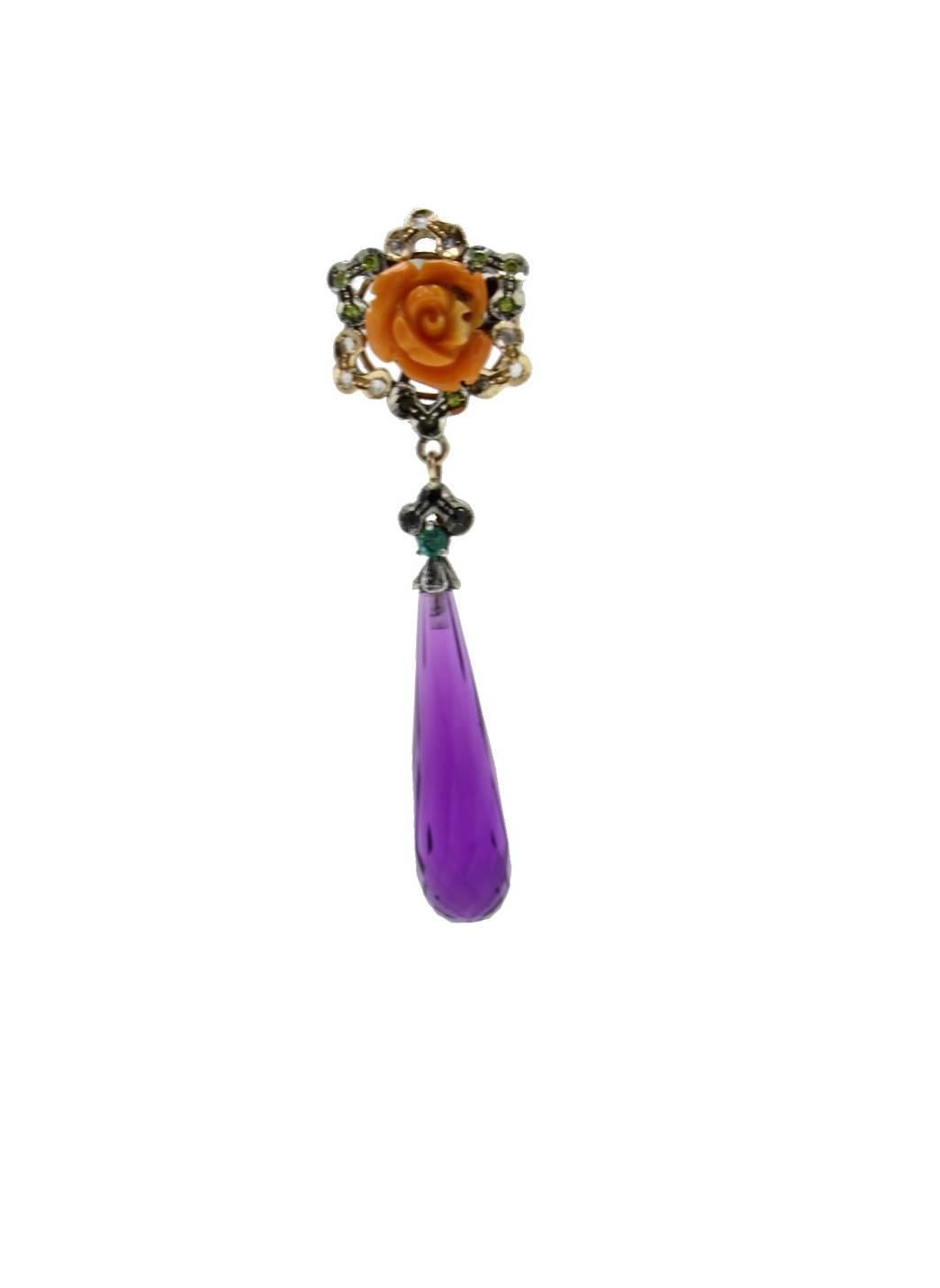 Dangle earrings in 9kt yellow gold and silver both composed of a rose carved coral surrounded by diamonds and yellow sapphires linked to a drop od amethyst by an emerald and three blue sapphires.

gold 3.05gr
silver 2.61gr
diamonds 0.22kt
gems