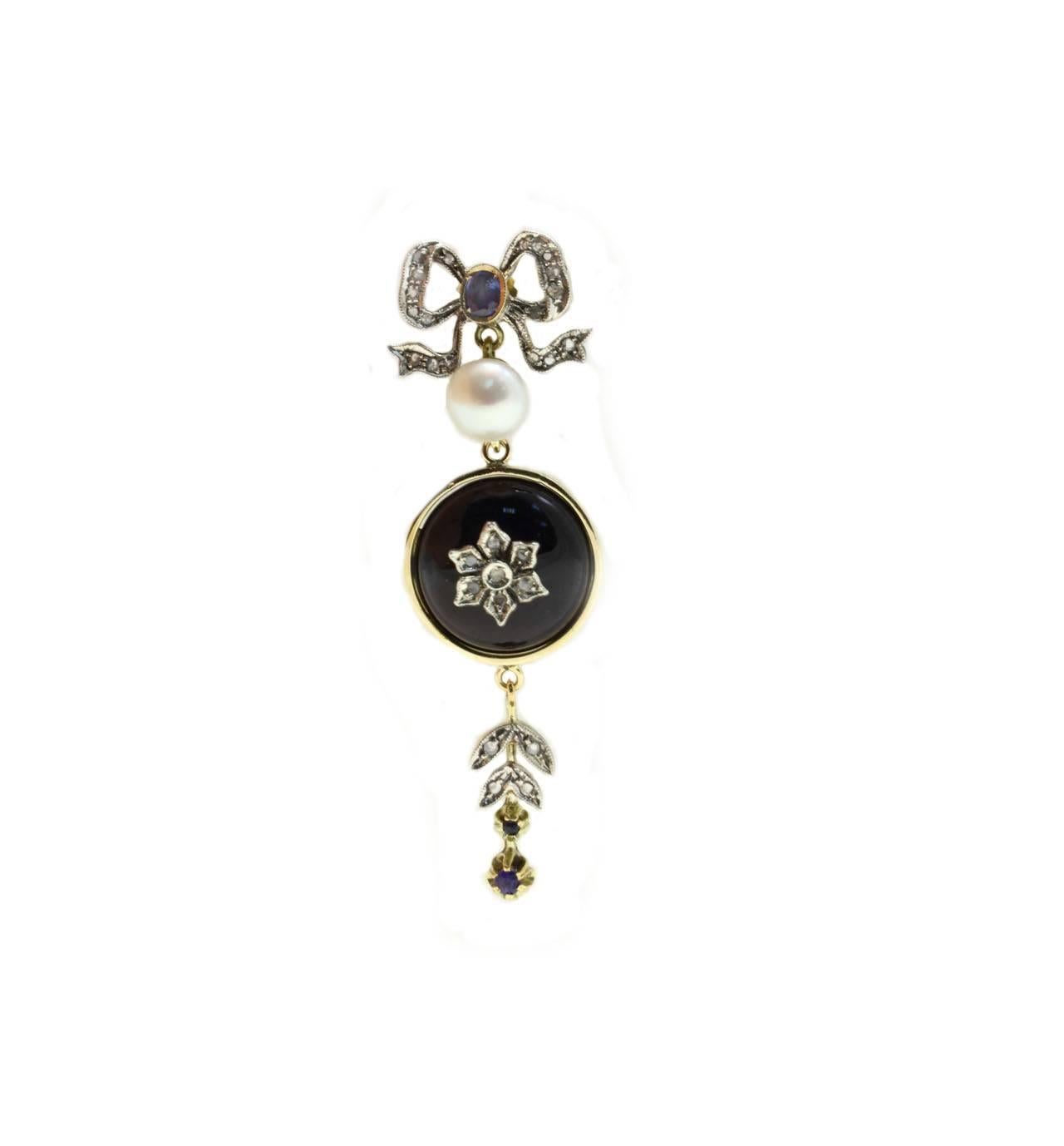 Dangle earrings in 14kt yellow gold and silver composed of a central onyx dome with a flower covered in diamonds on it. On the top there is a diamonds bow embellished with a blue sapphire and a pearl, instead, on the bottom a charm of diamonds and