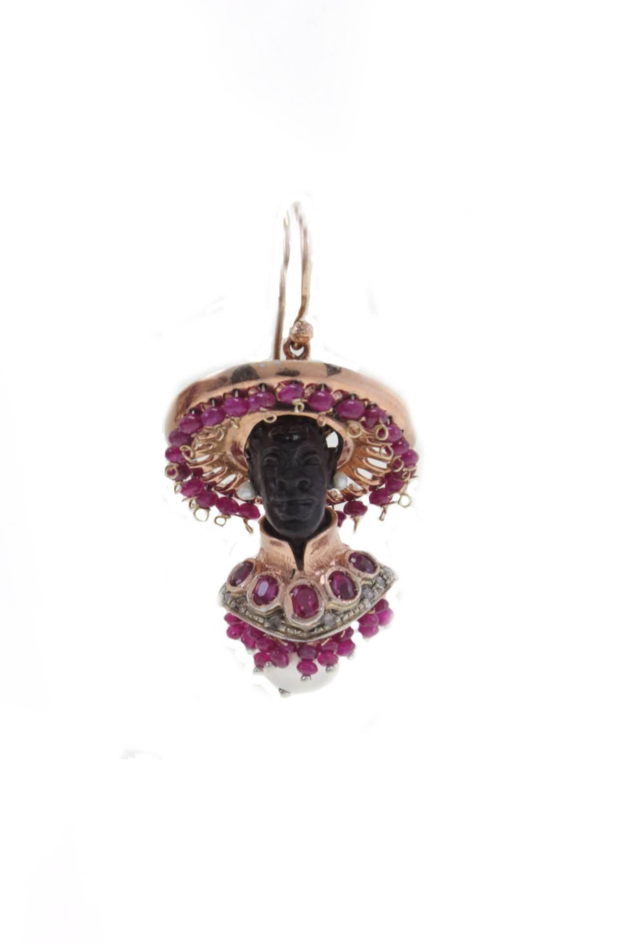 Moretti earrings in 9kt rose gold and silver, both composed of a carved ebony face with pearl earrings and a dress covered in diamonds and rubies with a pearl on the bottom. The hat is composed of dangle rubies all around and diamonds on the
