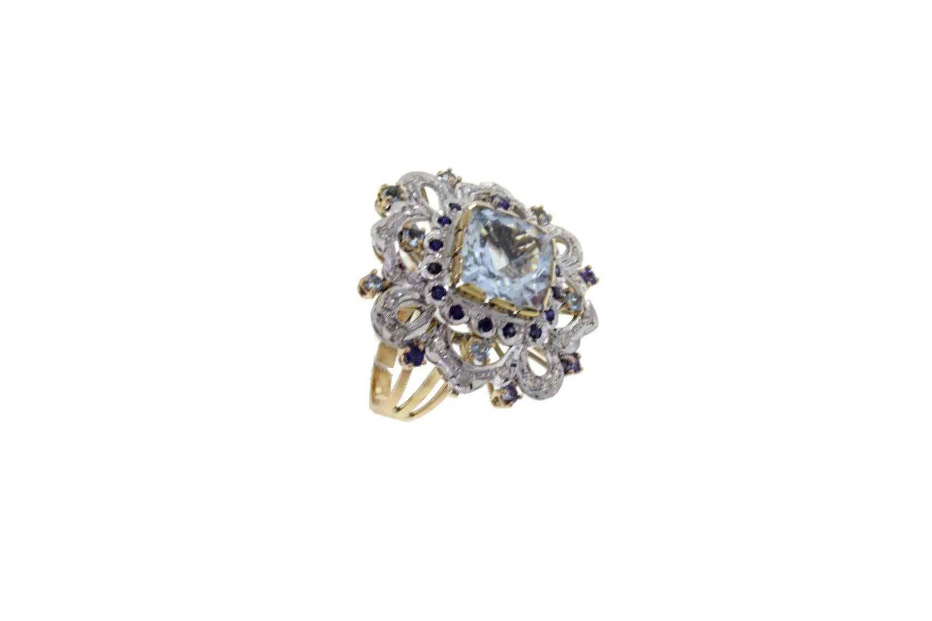 Cocktail ring in 14kt yellow and white gold composed of a central aquamarine surrounded by diamonds and blue sapphires.The origin of this ring goes back to the 1950s. It was totally handmade by Italian master goldsmiths and it is in perfect