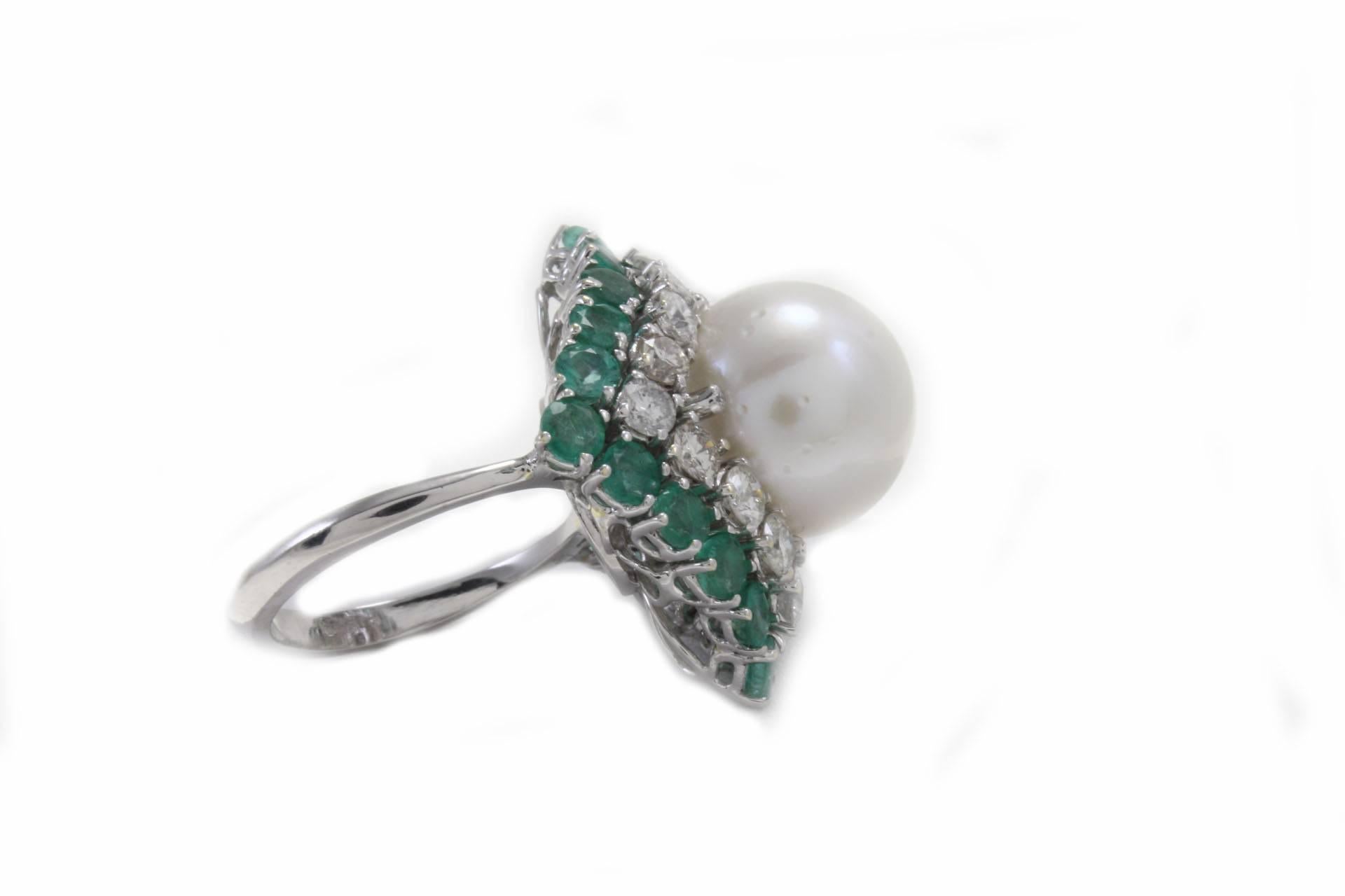 

Charming cluster ring, mounted in 14K white gold, with a rhombus shape realized with 3.50 g of white australian pearl (13 mm) in the center and embellished all aroud by 2.05 ct of diamonds and 2.95 ct of emeralds.
Diamonds 2.05 ct
Emeralds 2.95