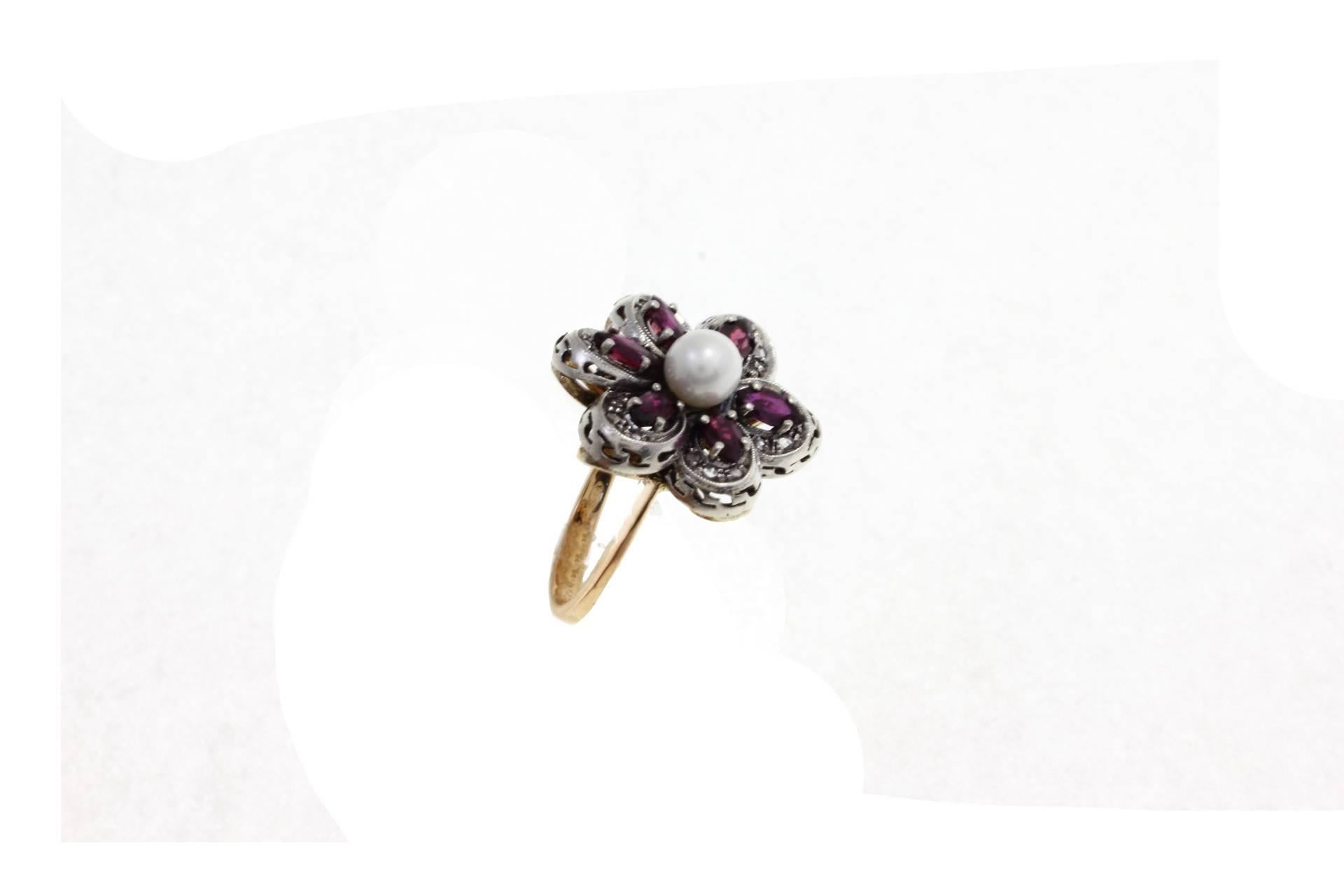 Flower shaped ring in 14kt yellow gold and silver composed of a central pearl surrounded by rubies petals and diamonds.

diamonds 0.13kt
rubies 2.31kt
pearl 6 mm/0.23 inch
tot weight 9.5
r.f.  hea