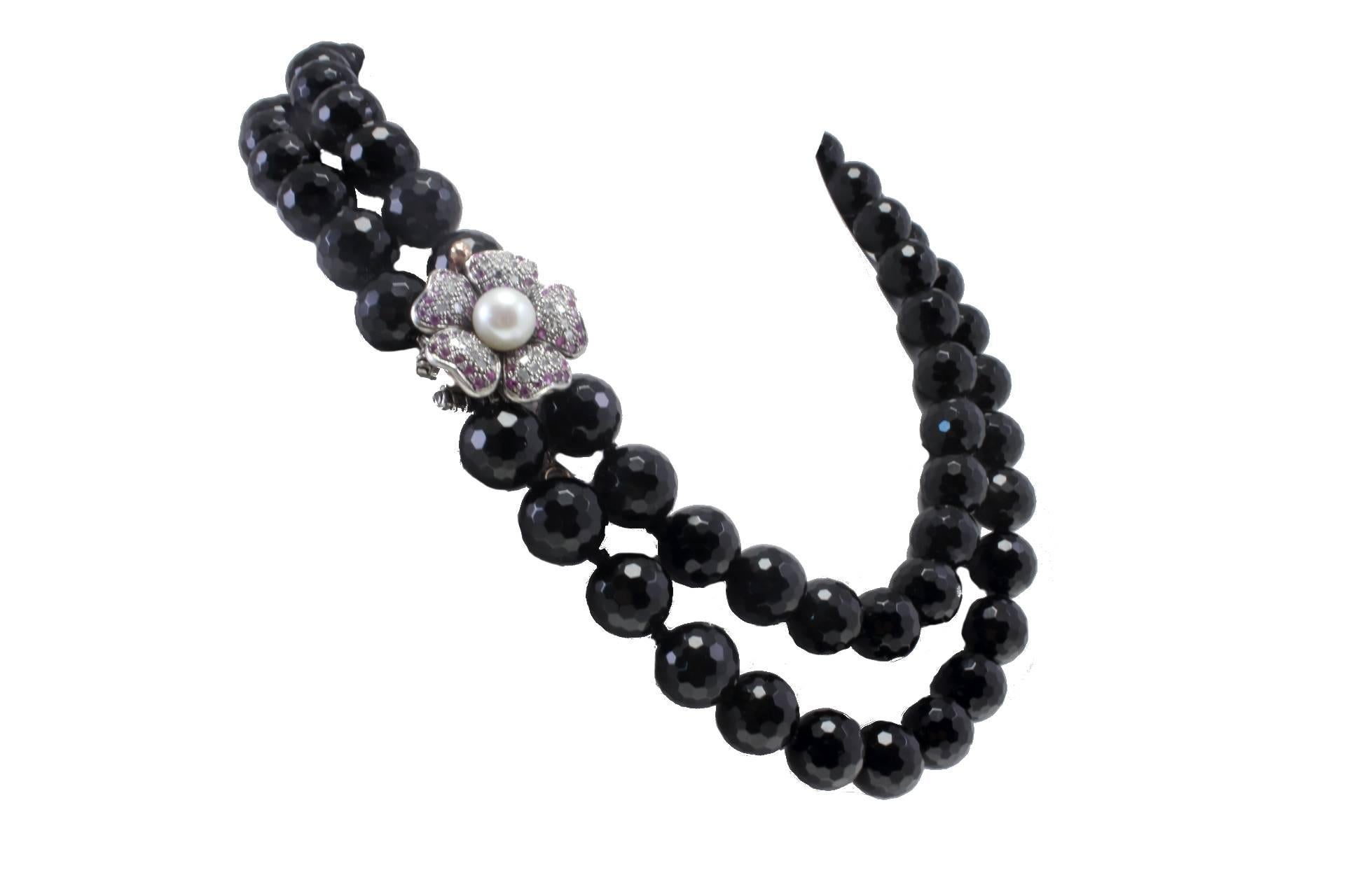 Black stone beaded necklace with a flower shaped clasp in 9kt yellow gold and silver covered in diamonds and rubies with a central pearl.

diamonds 0.3kt
rubies 1.72 kt
tot weight 178.7gr
r.f.  cch

We hereby inform our customers that in the case of