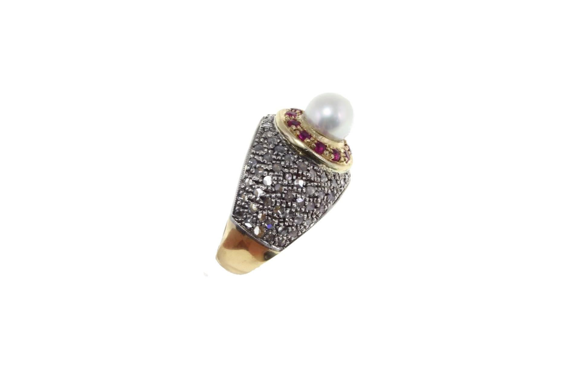 Elegant dome ring in 14kt yellow gold and silver composed of a central pearl surrounded by 12 shiny rubies all on an expance of encrusted diamonds.

diamond 0.73kt
tot weight 11.7gr
r.f.  ggch