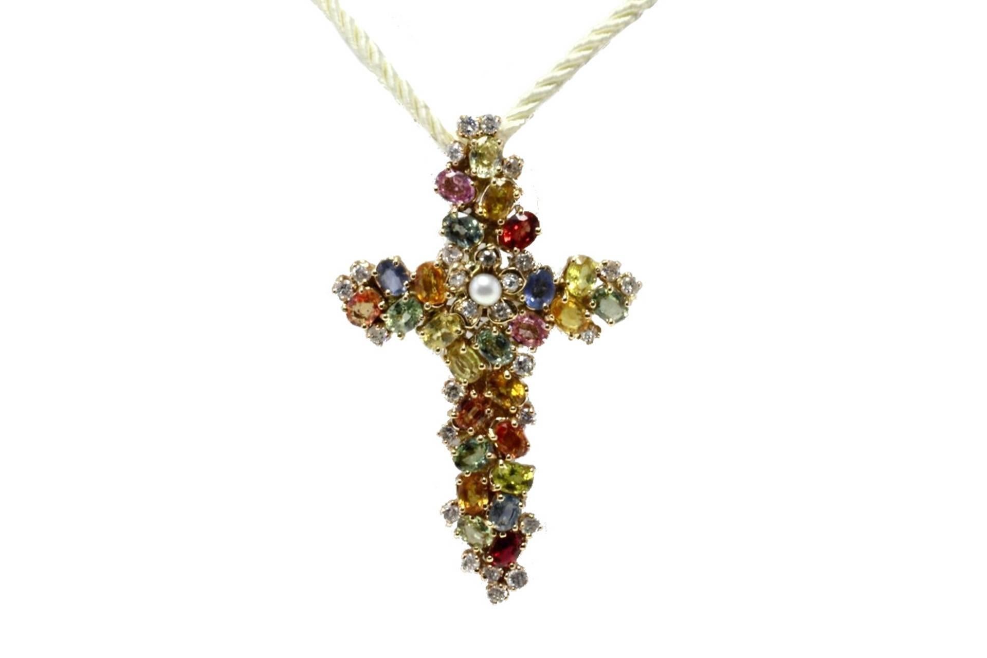 Shiny and coloured cross shape pendant in 14kt rose  gold comvered in encrusetd diamonds, rubies and multi-colour sapphires. In the center of the cross there is a diamonds flower with a central pearl to embellished all the pendant.

tot weight