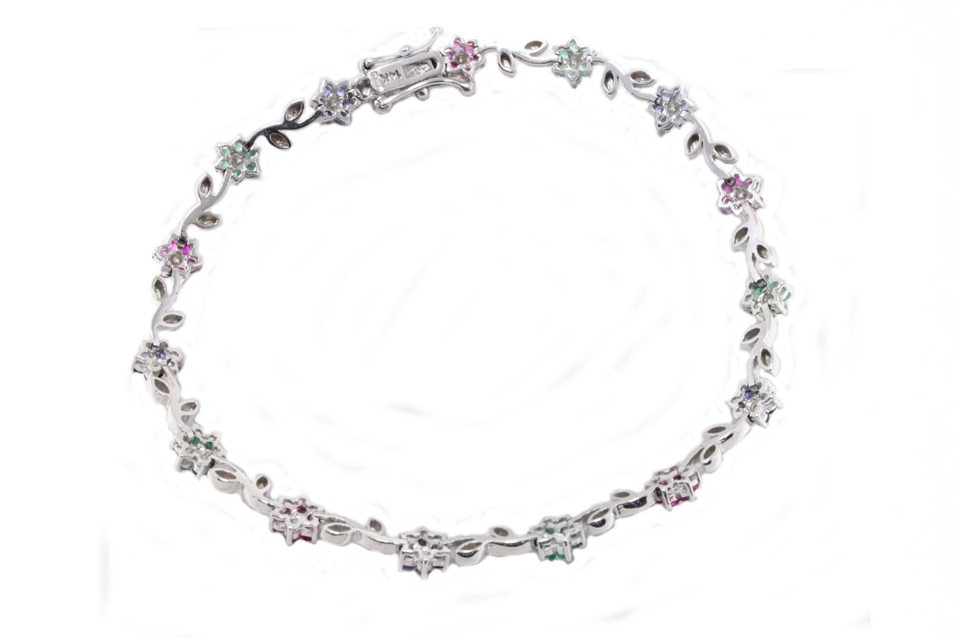

Sparkling link bracelet composed of flowers of blue sapphires, rubies and emeralds, with a diamond in the middle of them, all linked by shiny white gold leaves. All is mounted in 14K white gold. 
Tot weight 6.4 g
Diamonds0.18 ct
Emeralds, rubies,
