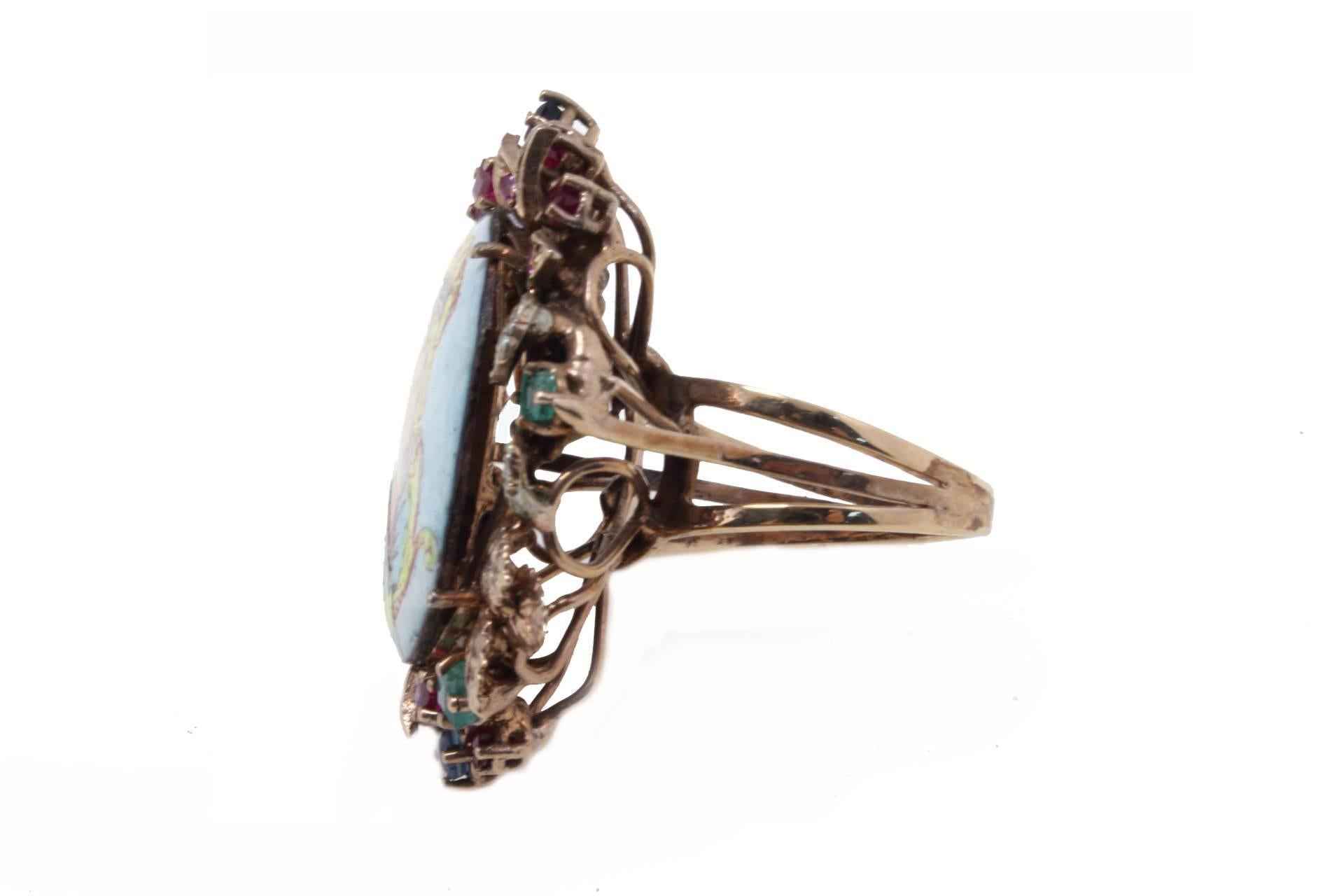 

Classic vintage ring composed with a frame of  diamonds, emeralds, rubies and blue sapphires that surrounding a miniature. All is mounted in 9K rose gold and silver .
The miniature present a little crack on the bottom left side.
Ring Size: ITA 16