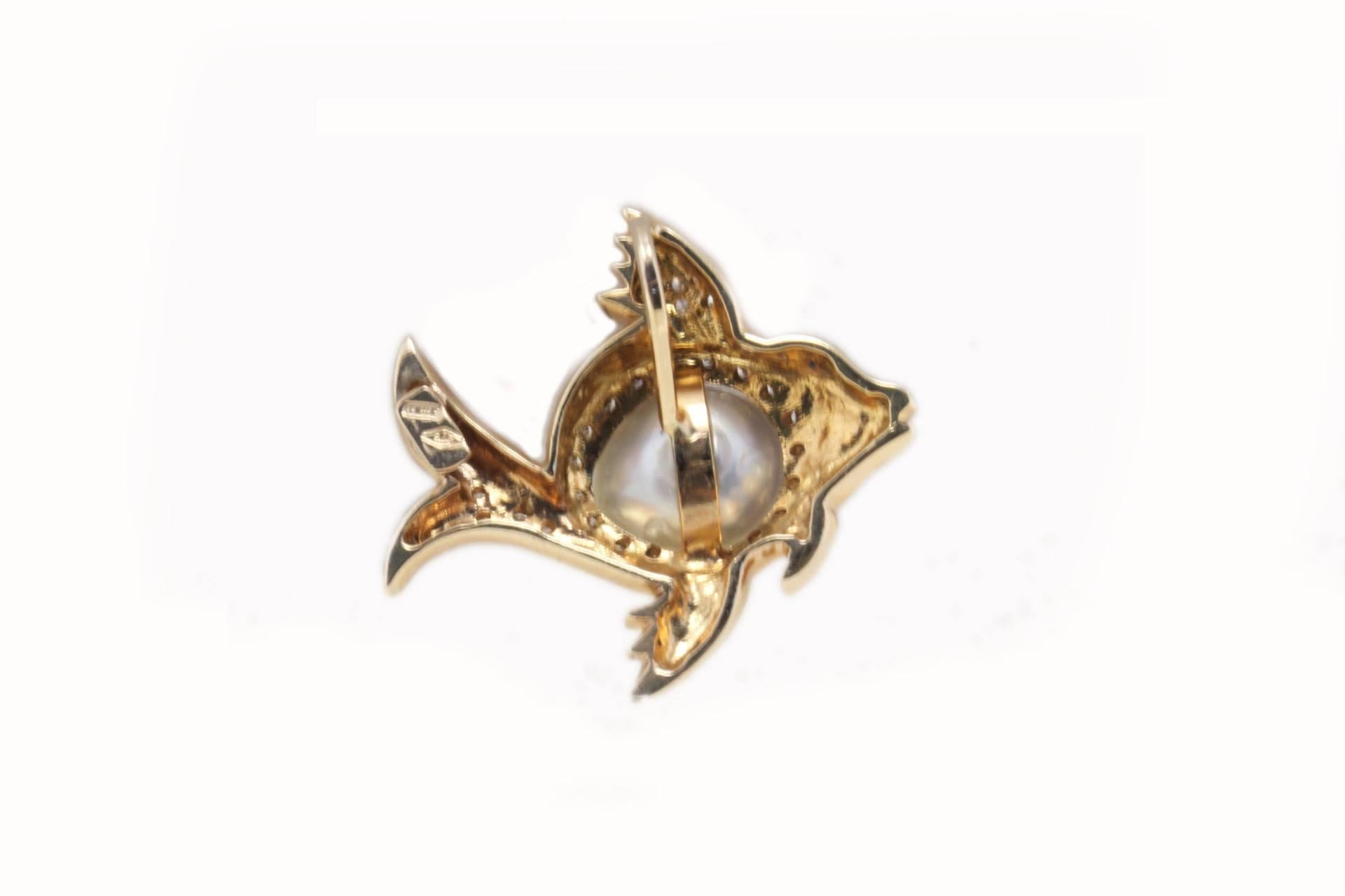 Sparkling fish shape pendant, mounted in 9K rose gold, composed of 1.40 g of white pearl in the center, tail and fins studded by 0.55 ct of diamonds,  and 0.04 ct of ruby like eye.
Tot weight 6.2 g
Diamonds 0.55 ct
Ruby 0.04 ct
Pearl 1.4 g /  10