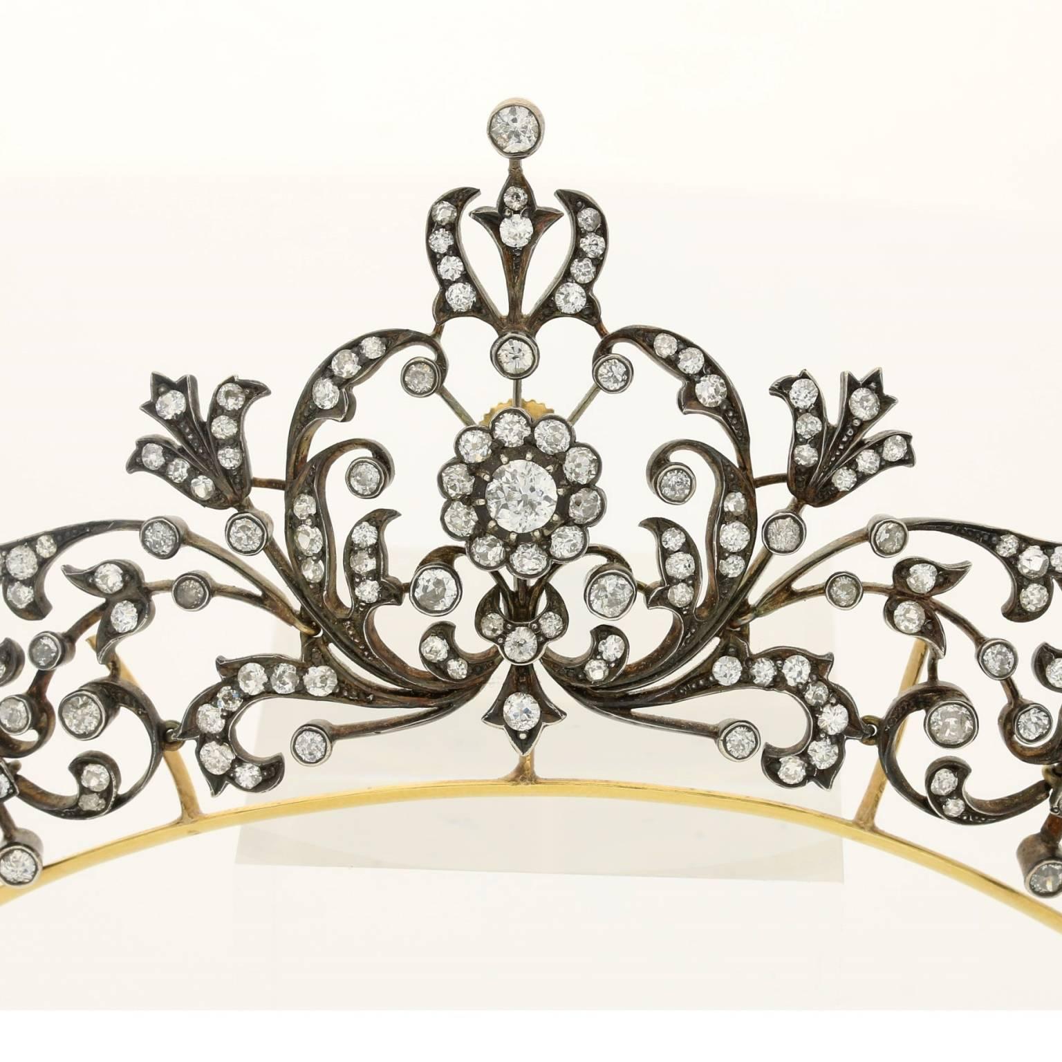 Diamond tiara / necklace of scrolling floral and foliate design with central old mine cut diamond cluster among a graduated openwork panel raised on a plain frame with detachable backchain mounted in silver and gold.

Victorian circa