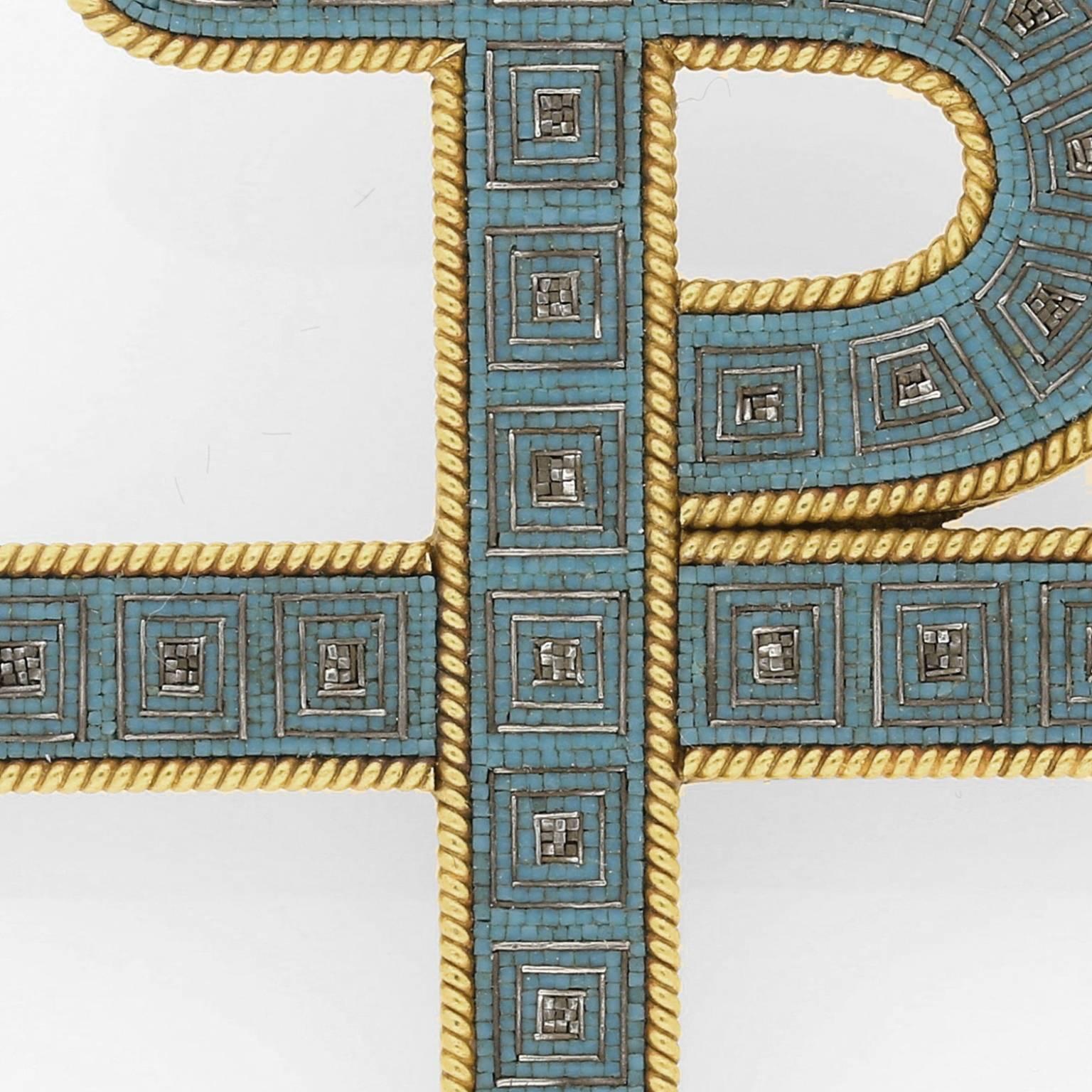 The exceptionally crafted brooch of staurogram form depicting the overlapping Greek letters T ‘tau’ and P ‘rho’ in yellow gold set throughout with an exquisitely fine micromosaic pattern in blue and silver colour tesserae within a gold twisted