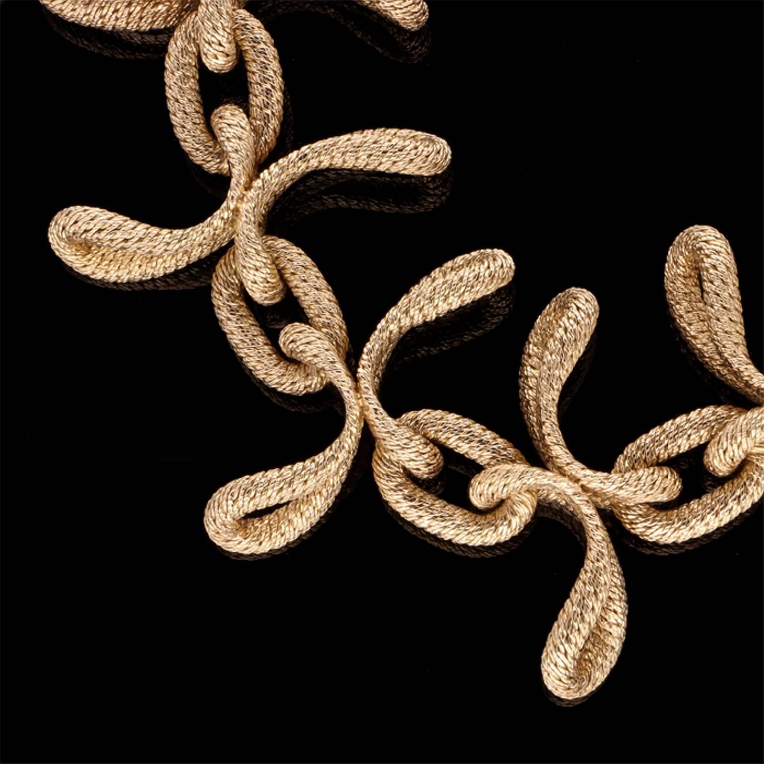 The stylish bold necklace of textured woven gold with oval links and six large asymmetric curved openwork propeller style motifs to the front, interspersed by further oval links, all in 18ct yellow gold.

18ct yellow gold with makers signature and