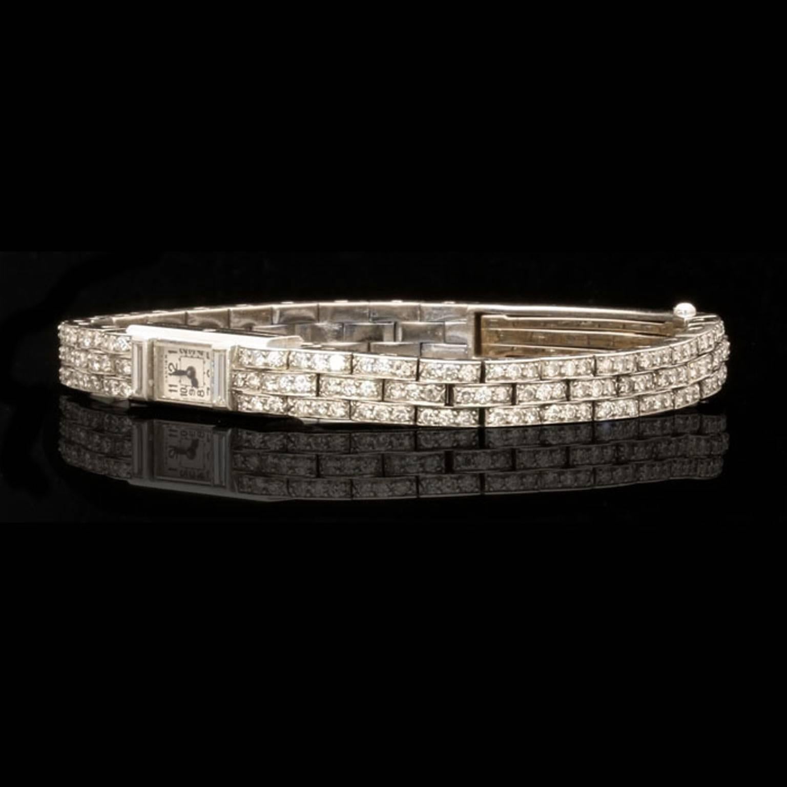 The elegant ladies watch composed of three rows of articulated rectangular links to a rectangular white dial with black Arabic numerals and hands, signed Cartier.

Single cut diamonds estimated to weigh a total of approximately 2.8cts

Platinum