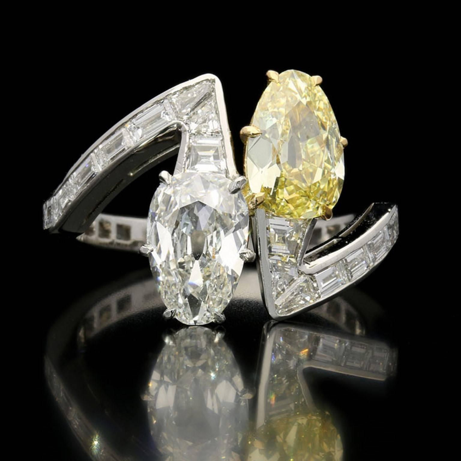 The wonderfully stylish contemporary ring set with an unusual pair of old cut pear shaped diamonds, a 1.01ct Fancy Intense yellow and a 1.03ct H VS2, claw set and facing in opposite directions along the finger, each to the head of an angular row of