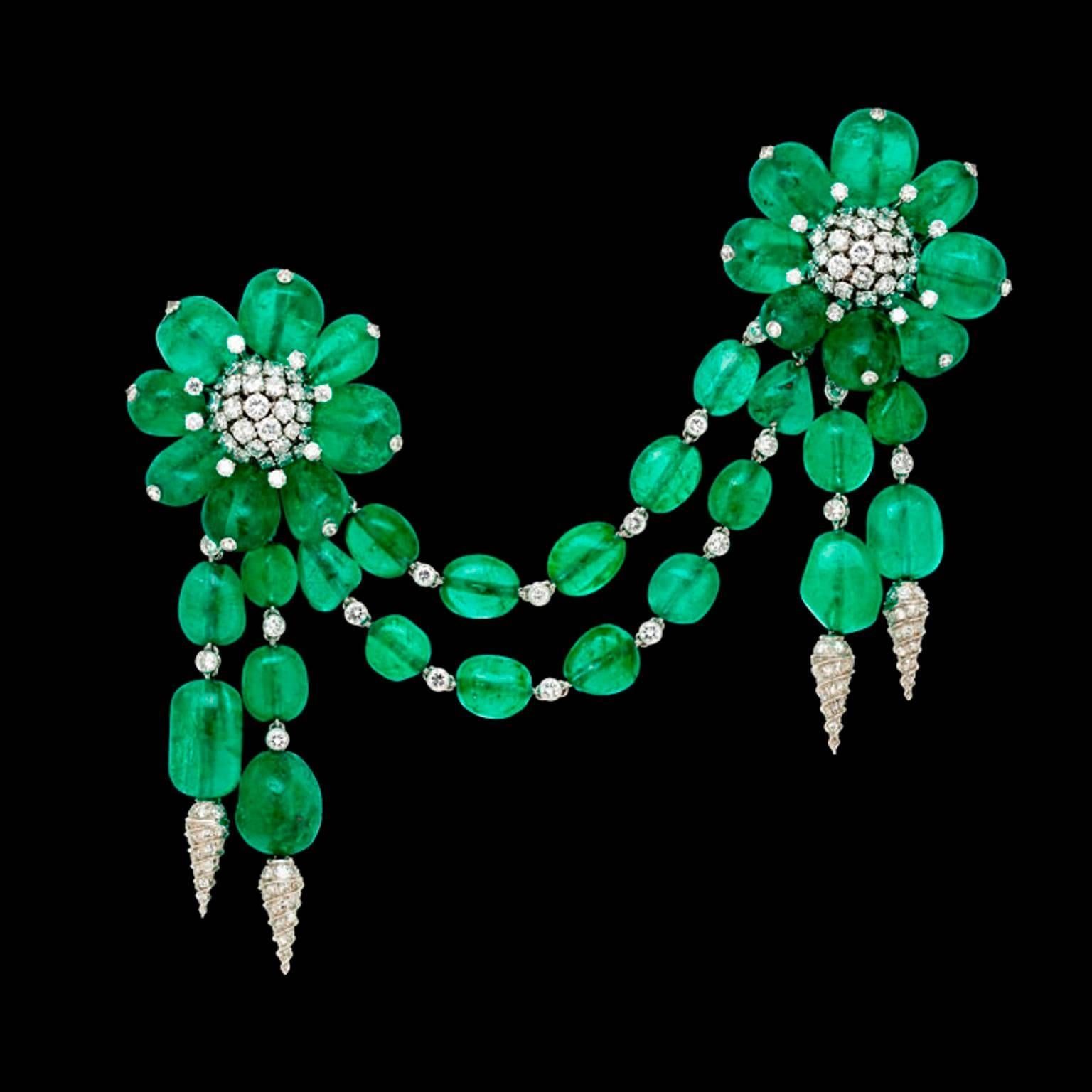 The devant de corsage designed as two flower heads each with polished emerald bead petals surmounted by a single diamond detail surrounding a round brilliant-cut diamond cluster centre, linked by a double row of emerald beads interspersed with bezel