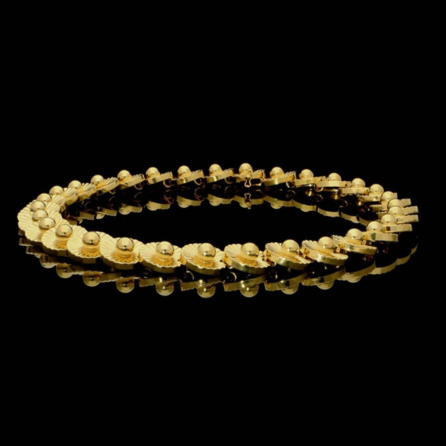The necklace formed of thirty one highly polished overlapping concave links designed as stylised daisies with a fluted pattern and set to the centre with a gold sphere, with concealed clip fastening and safety catch.

18ct yellow gold with makers