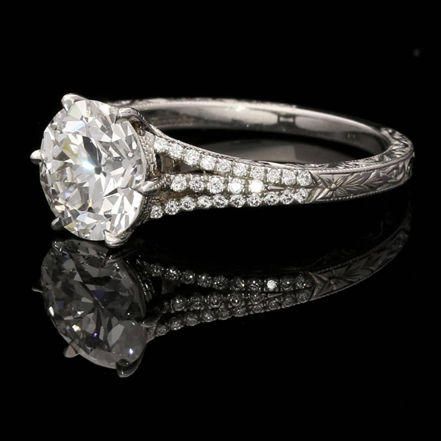 The ring set with a charming round old European cut diamond weighing 2.05ct and of G colour and VS2 clarity six claw set between unusual triple split diamond set shoulders to an ornately hand engraved finely crafted platinum mount.

2.05ct G VS2