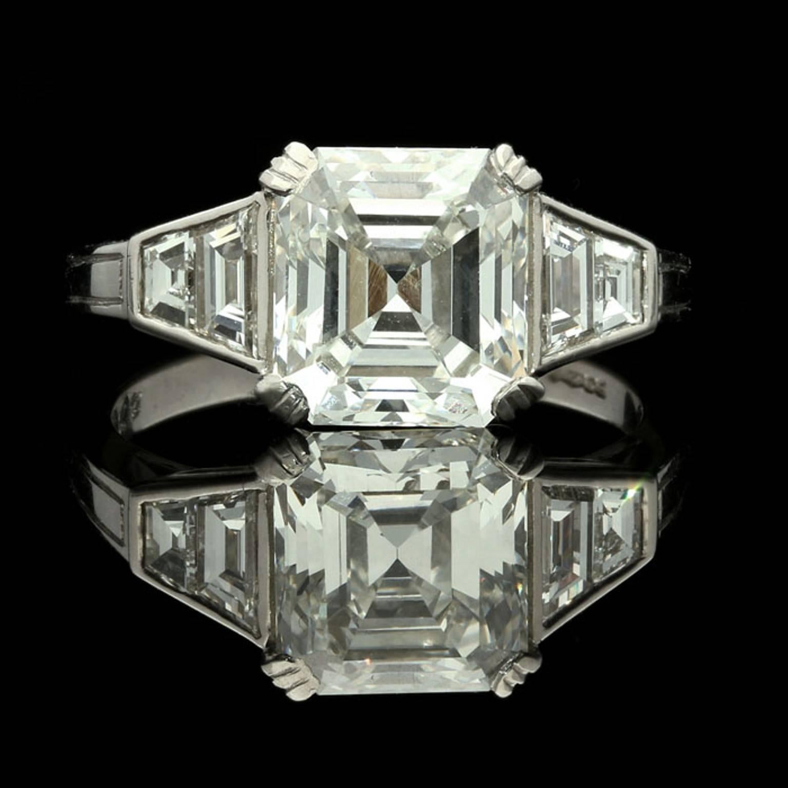 A stunning Asscher diamond ring by Hancocks, set to the centre with a beautiful Asscher cut diamond weighing 2.77 carat corner claw set between elegantly tapering shoulders each with two rub over set trapezoid diamonds, all in a finely handmade