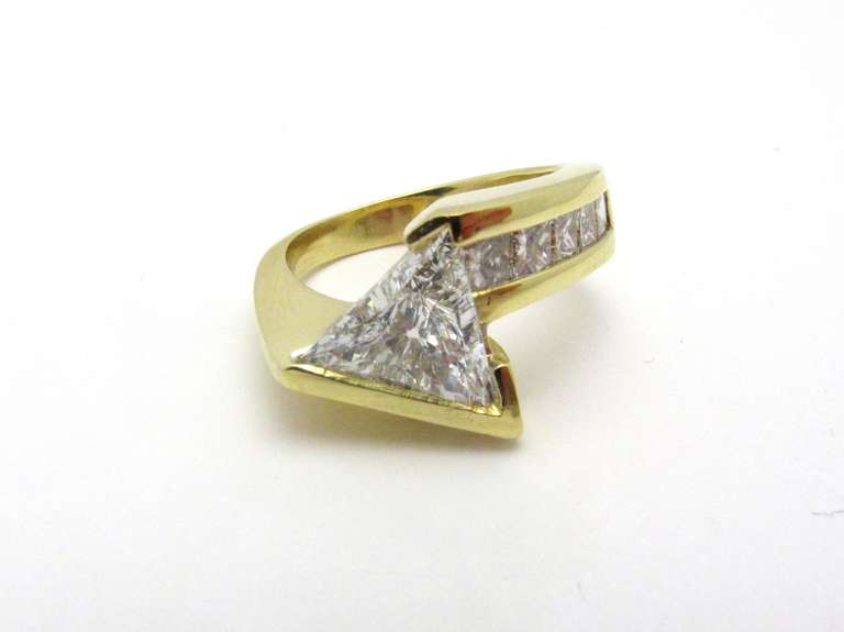 John Atencio diamond and 18kt gold ring mounted with a trillion-cut diamond of total weight 1.52cts color E Clarity SI1 accompanied by an EGL certificate #US67051101D. Flanked on one side are five channel-set princess-cut diamonds of approximate