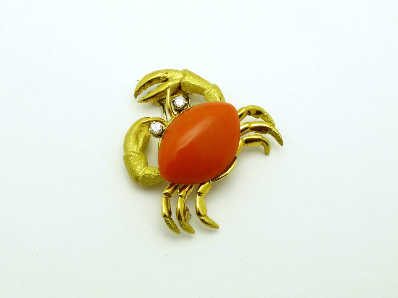 Beautiful modeled yellow gold crab brooch with a polished and Florentine finish.  It is set with orange Mediterranean coral and round brilliant-cut diamond eyes.