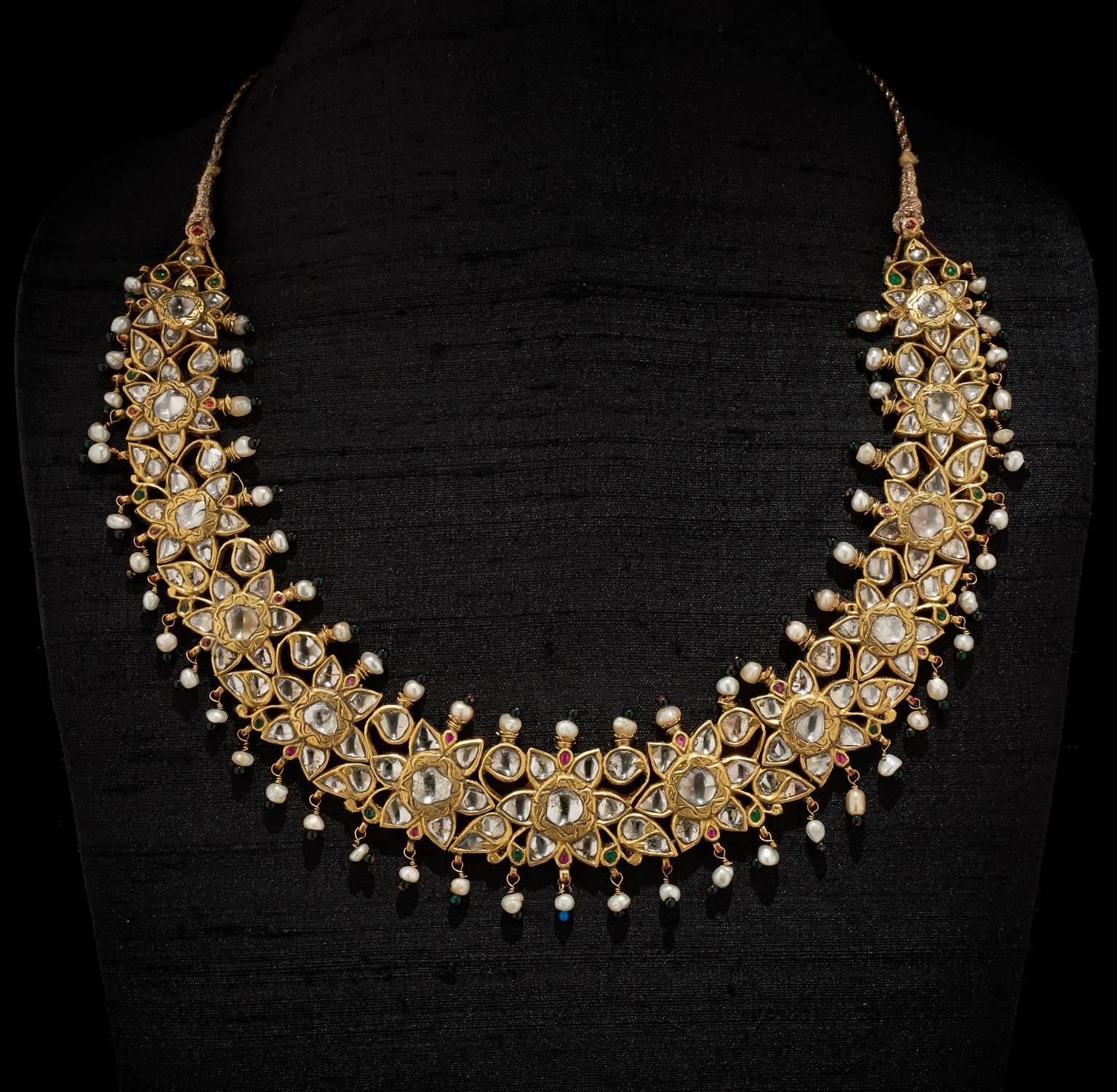 Necklace
Jaipur, Rajasthan, India
20th Century

Fabricated from gold set in kundan (traditional pure gold setting) technique with diamonds in the form of lily flower-heads and leaf motifs. The top and bottom edge are strung with pearls and glass