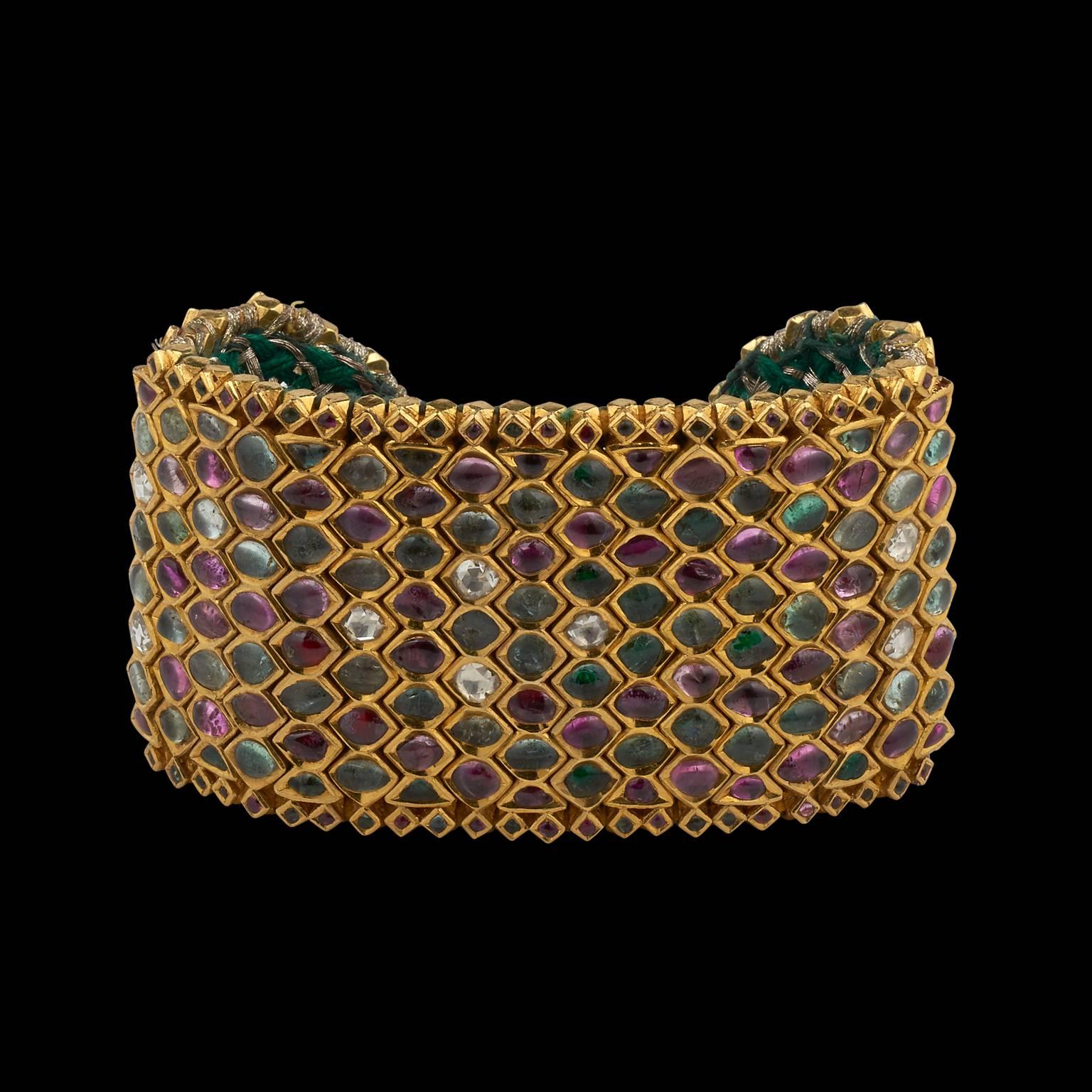 Armlet / Cuff
Mughal or Deccan, India
18th Century

Fabricated from pure gold, flexible with interlocking vertical units, each set with diamonds, rubies and emeralds. The semi-circular ends are set with similar precious gemstones forming bird
