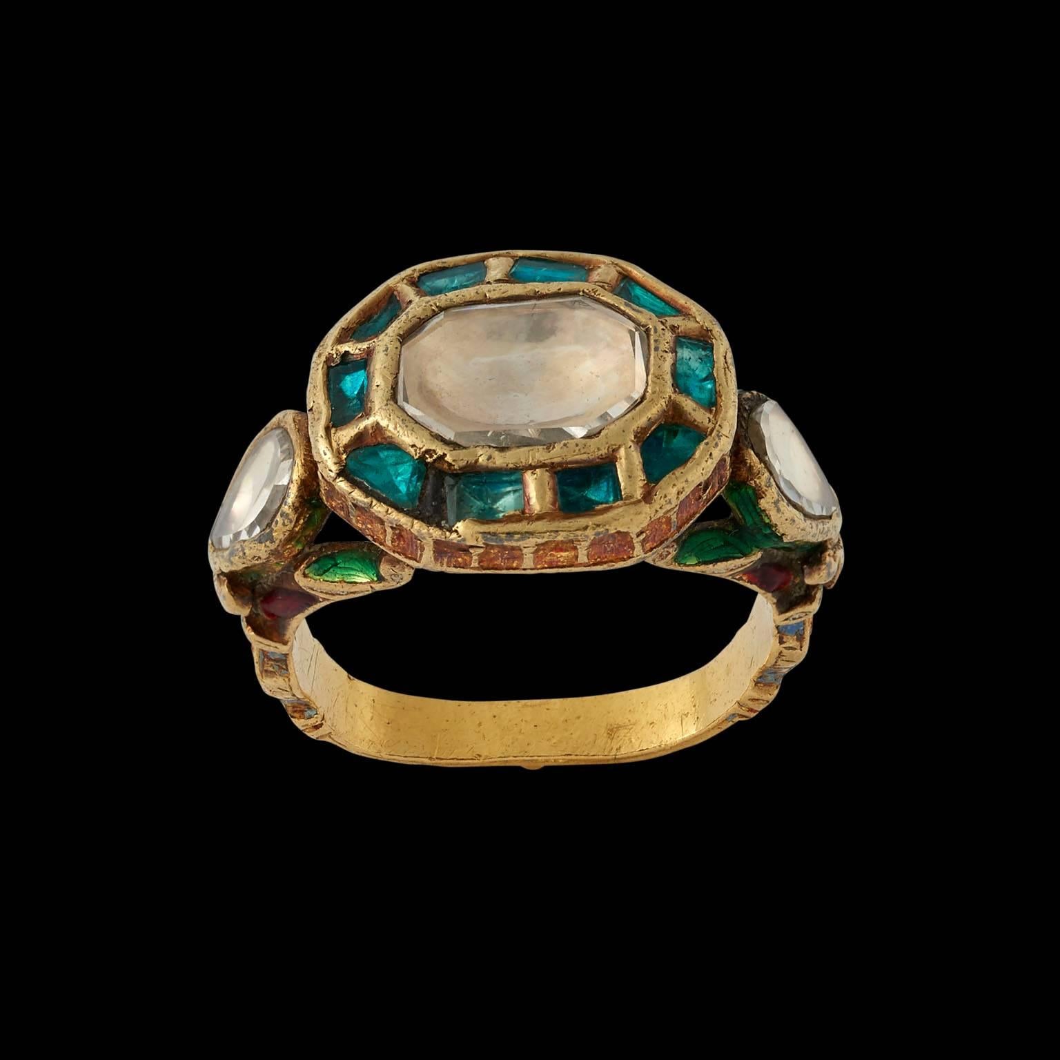 Ring
Rajastan, North India
19th century

Gold, enamel on the reverse, with a central diamond in a surround of emeralds and flanked by two diamonds on either shoulder.

UK Finger Size K