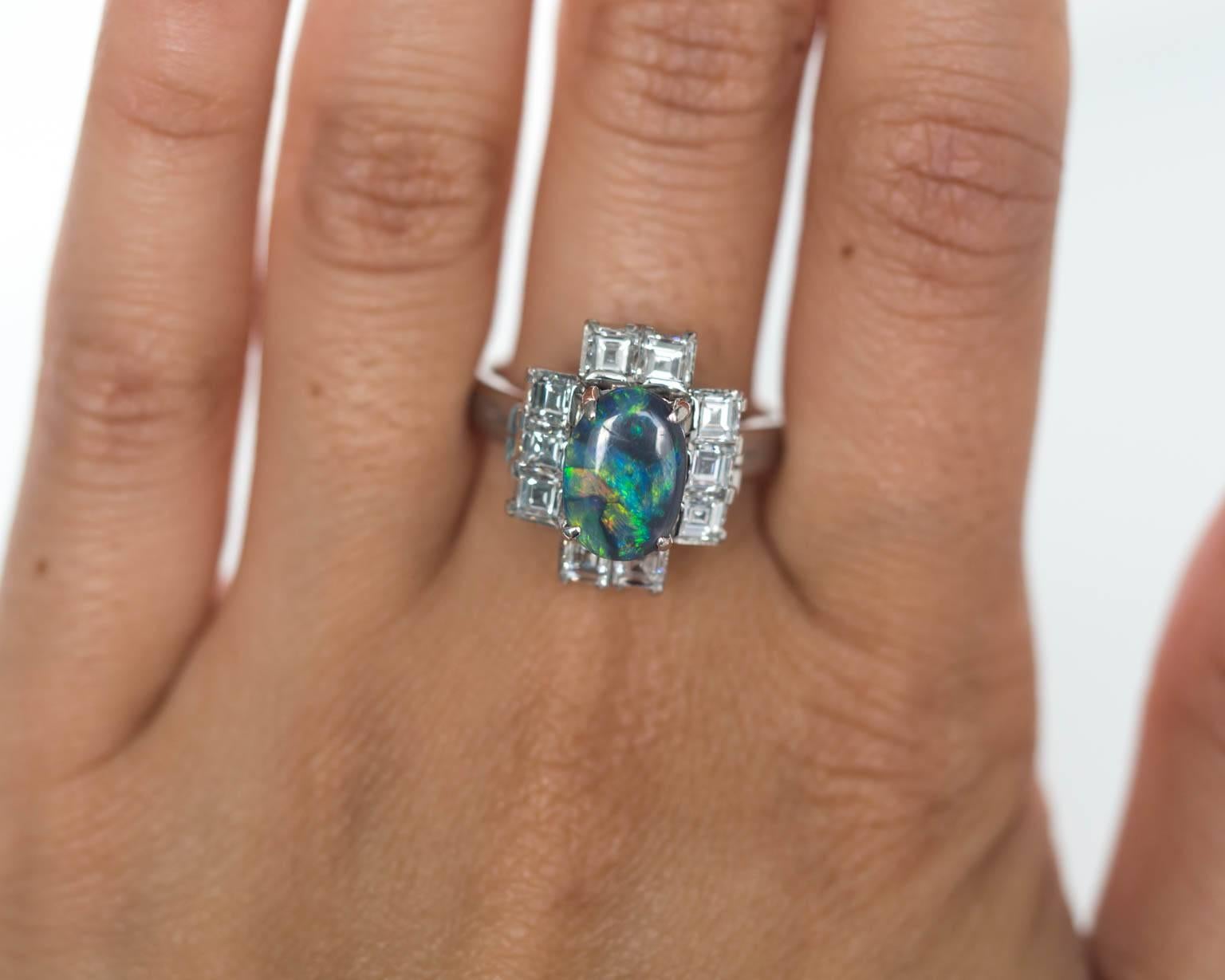 Here we have an absolutely stunning Black Opal and Asscher-Cut old cut diamonds deco jewel from circa 1927! This center stone, a *gorgeous* opal, oval shape has strong hues of neon green and black is prong set with 4 prongs. The ring is truly very