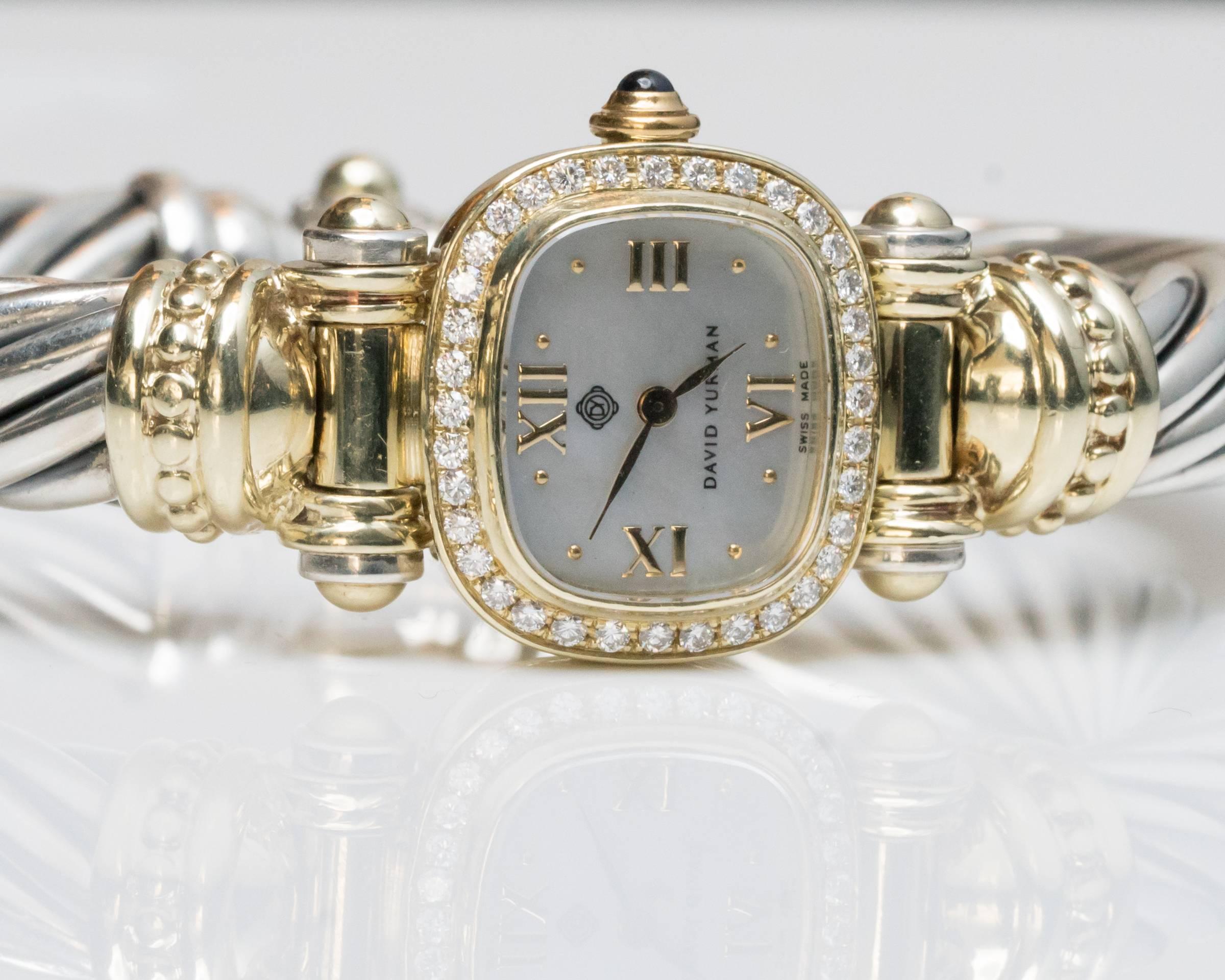 Classic David Yurman cable Bangle Watch with factory diamond bezel and sapphire cabochon crown. The dial is a rare Tahitian Mother-of-Pearl with gold hour markers. Measures 24mm wide with crown. Bangle bracelet is a medium size and will fit most