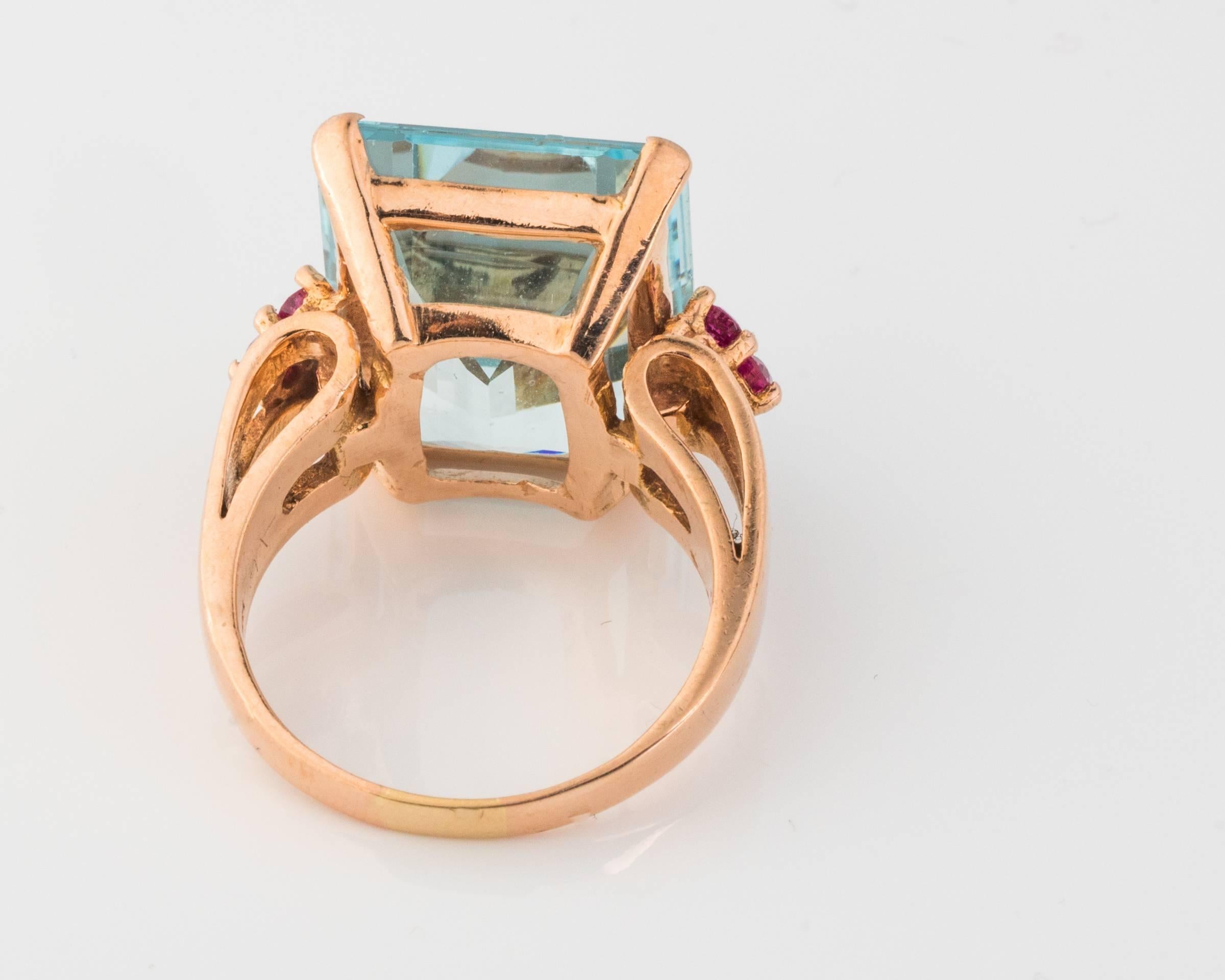 Retro Vintage 14kt Rose Gold Ring ft. Ornate Step-Cut Aquamarine. 

The gemstone measures 18.5mm x 14.5mm and approximately 10 carats in size. Flanked by six round brilliant simulated rubies. The color play between soft blues of the aquamarine and