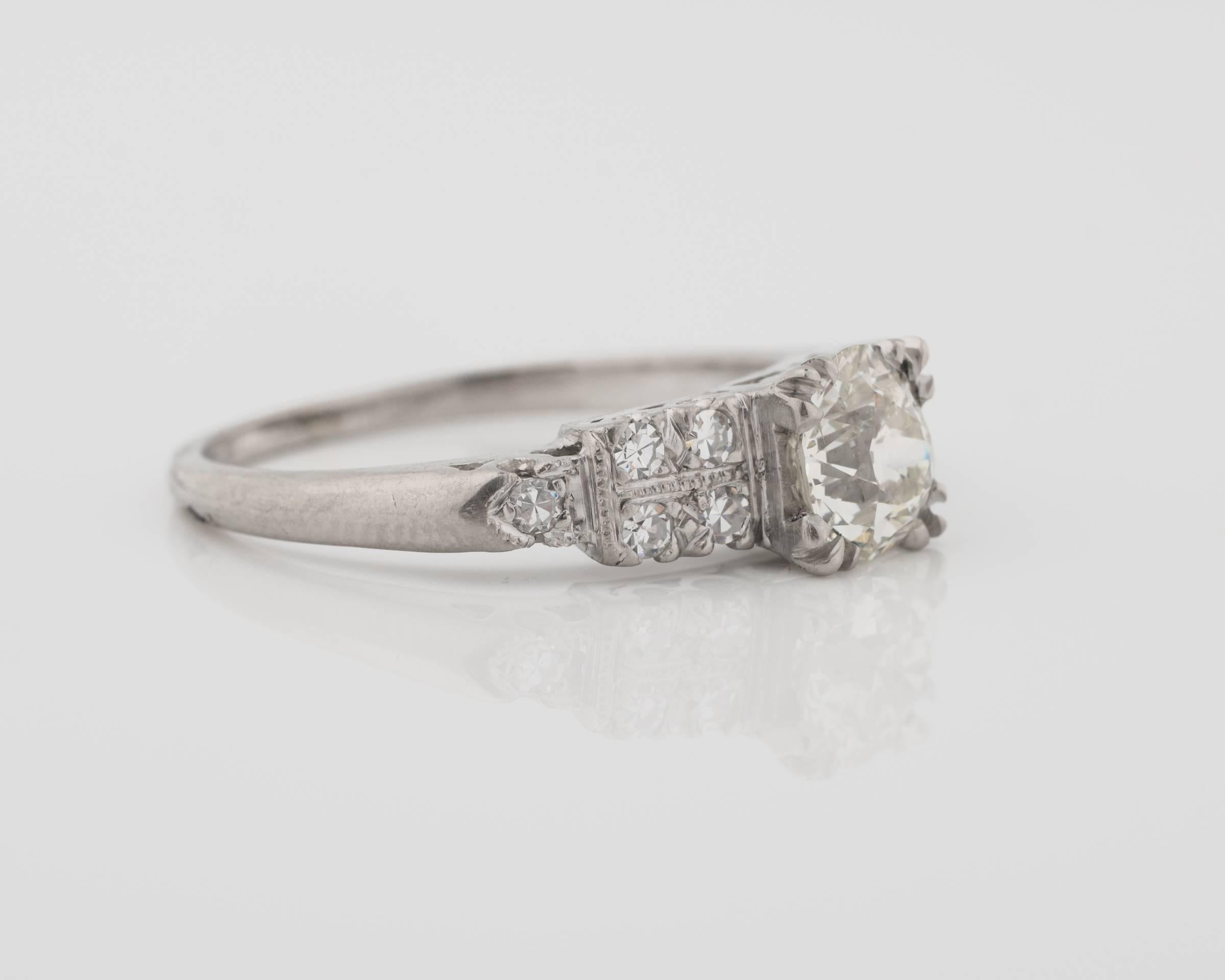 1930s GIA 1.01 Carat Old European Diamond Platinum Engagement Ring. Features a GIA Certified 1.01 carat center stone in a fishtail prong setting. 10 prong set Single Cut Round Accent Diamonds flank the center stone. The accent diamond settings have