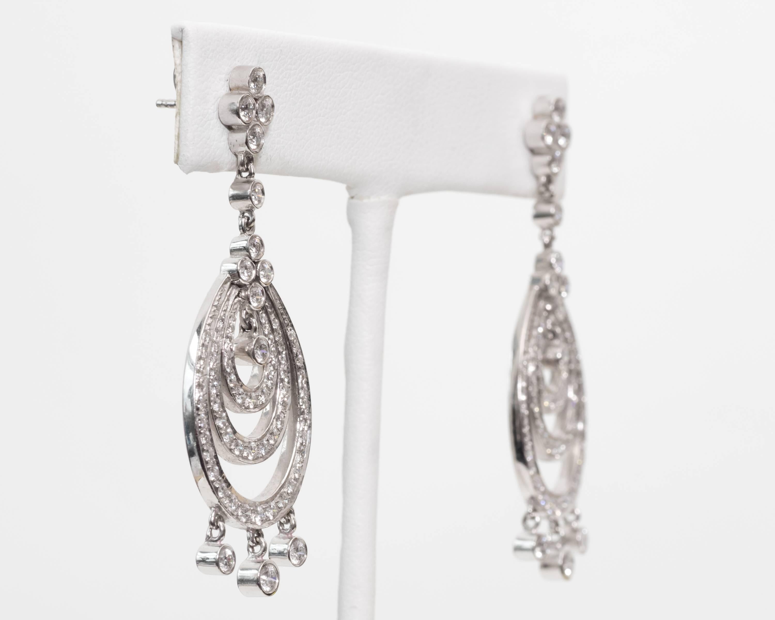 Luxurious earrings with stunning diamonds inlayed throughout the entire
surface area 
Diamonds are positioned along the pear-shaped cutouts on the front face of the earring
Additional diamonds are set in bezel frames that dangle with more diamonds