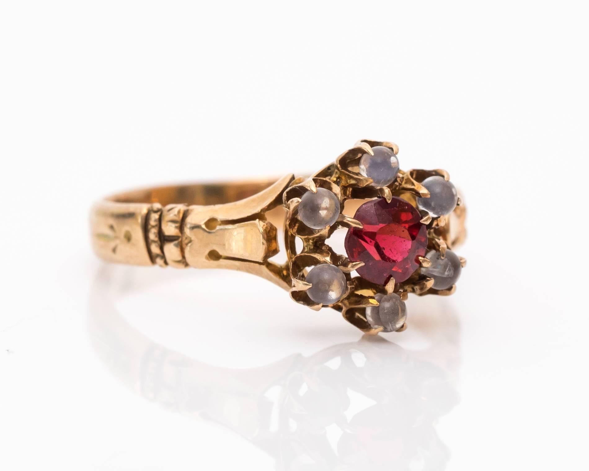 Ideal gift for a January Garnet Birthstone!

Deep pinkish red center stone complements the warn colors of the 9 karat yellow gold band. This romantic ring is full of shine and luster from both the garnet and six beaming moonstones. The traditional