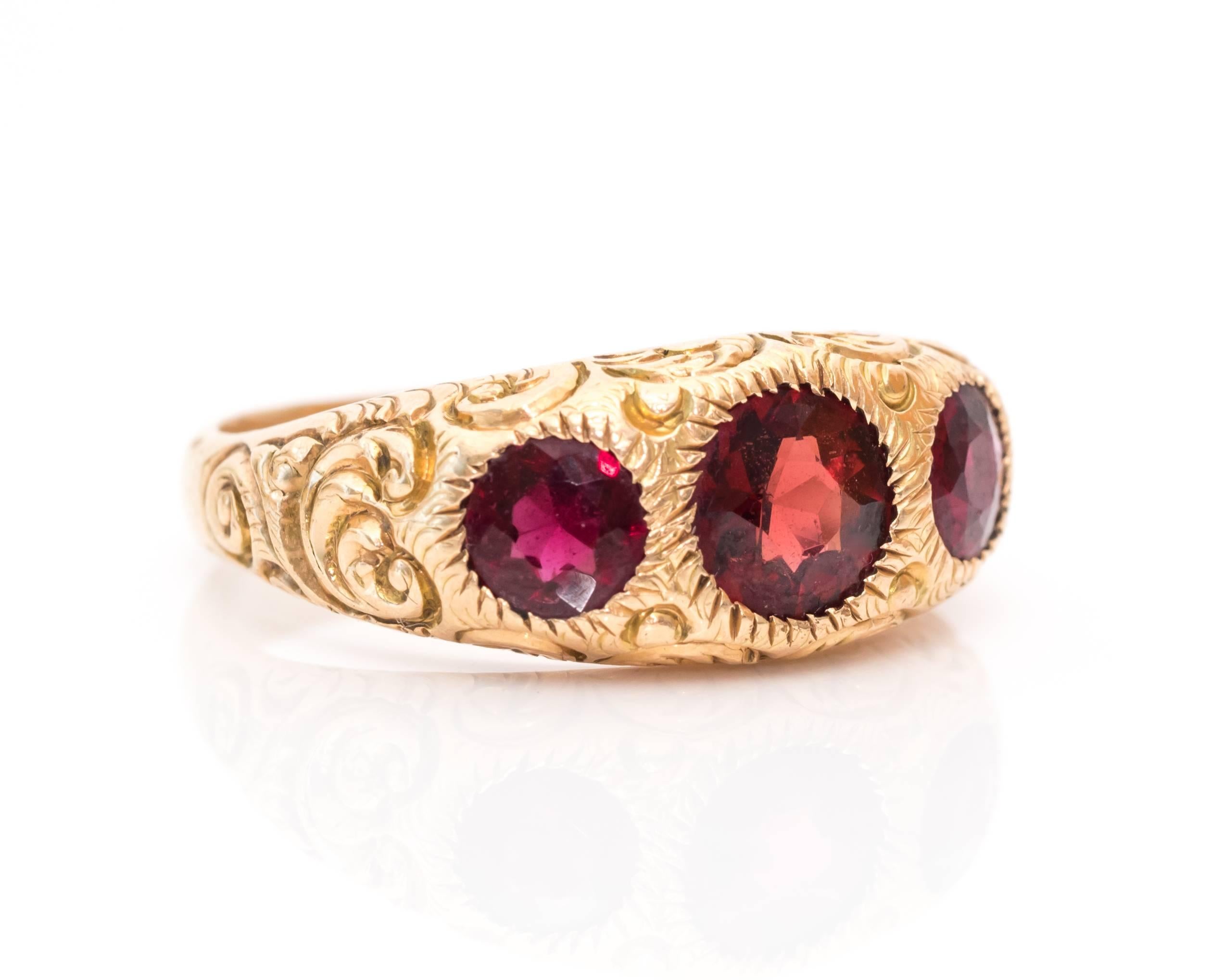 This ring is beaming with beautiful shine and color!
The ring is most likely made of garnets, but we cannot test the gemstones due to the mounting. The center stone is slightly larger than the two round stones bordering it on each shoulder. Each is